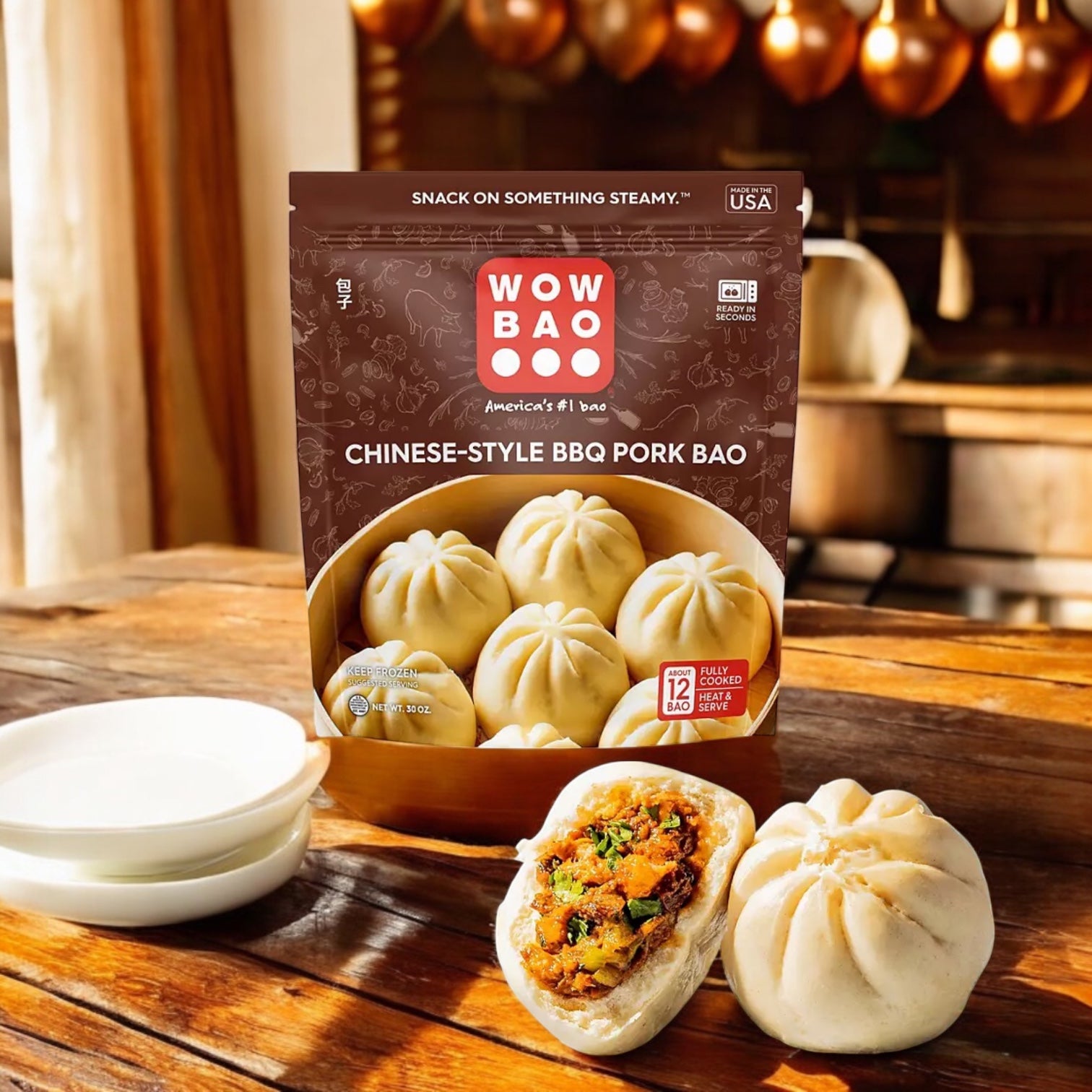 A package of Easy Lunches Wow Bao Chinese-Style BBQ Pork Bao Buns, Frozen, 30 oz 3 Count rests on a kitchen counter, with a split steamed bun showing its savory pork filling next to stacked dishes.