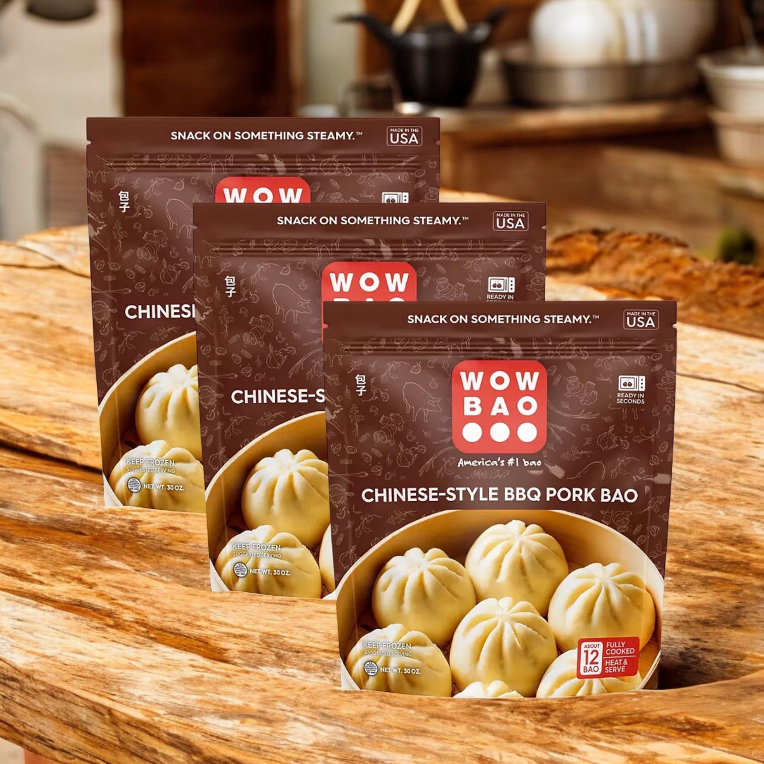 Three packs of Easy Lunches Wow Bao Chinese-Style BBQ Pork Bao Buns, Frozen, 30 oz 3 Count are arranged on a wooden surface with a kitchen background, showcasing these delicious steamed buns ideal for any meal.