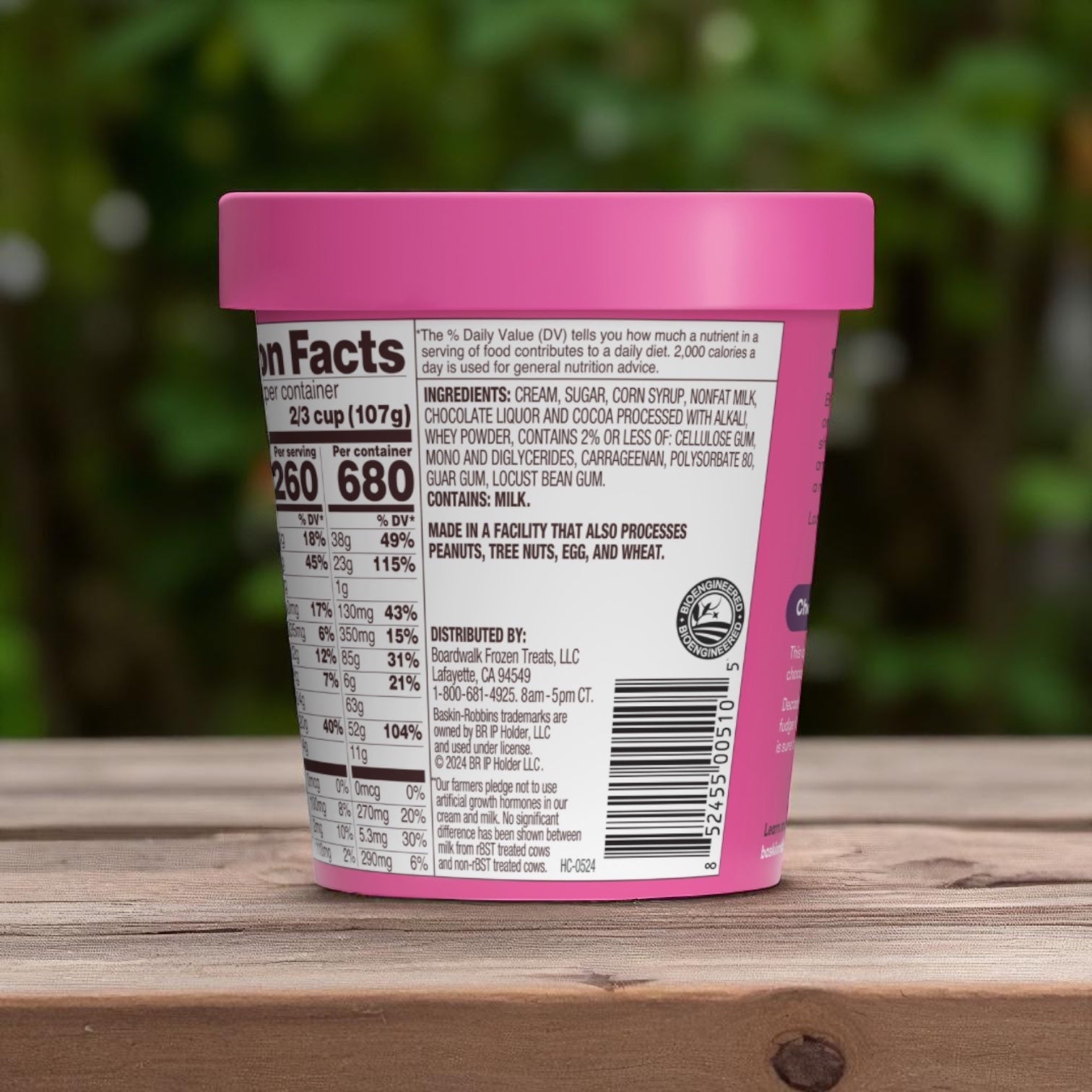 A 14 oz Baskin Robbins Ice Cream Chocolate Fudge container sits on a wooden surface, its label showing nutrition facts, ingredients, and allergen info—an ideal treat for any chocolate lover’s dessert craving.