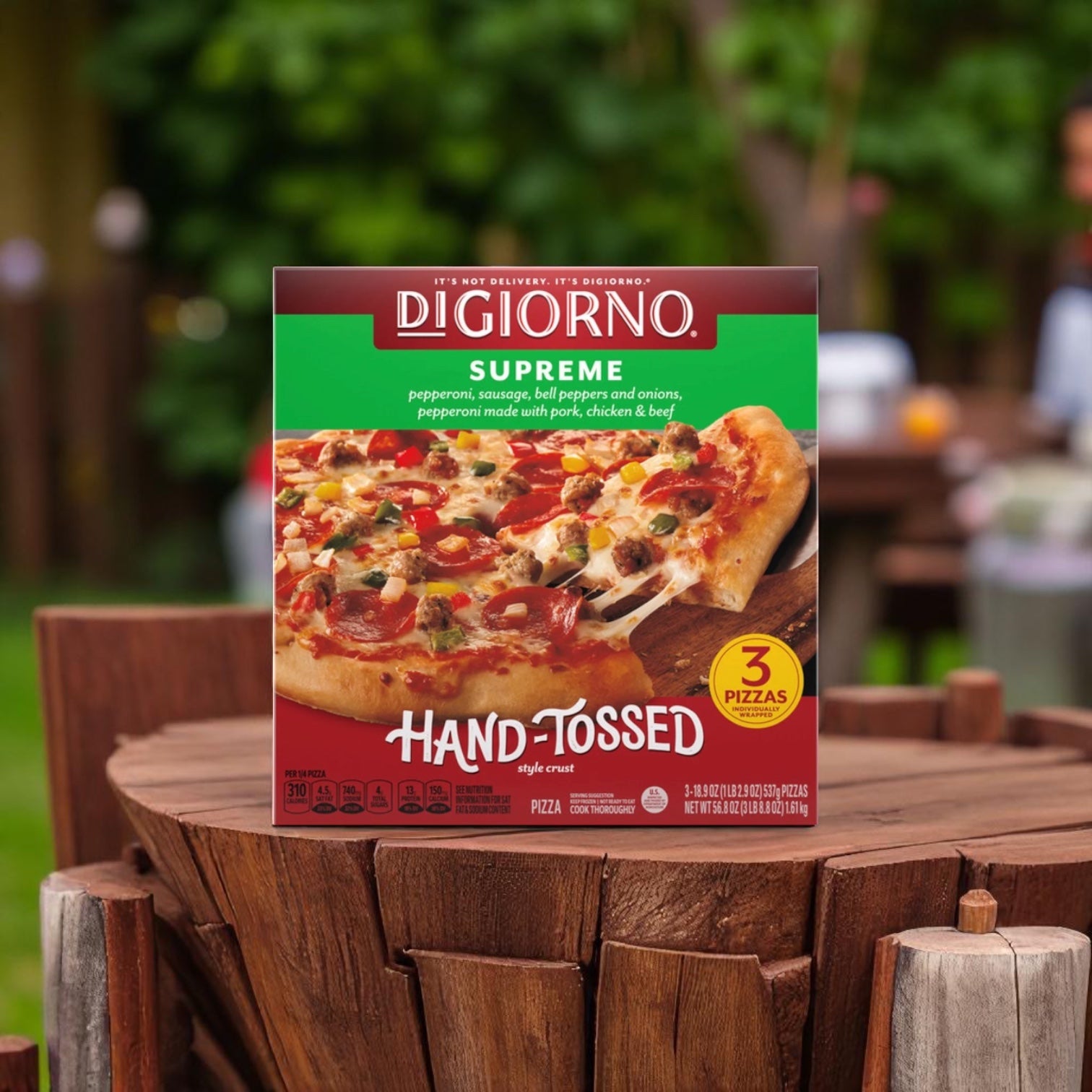 A DiGiorno Hand-Tossed Supreme Pizza, 18.9 oz from a 3-box pack, is on a wooden table outdoors.