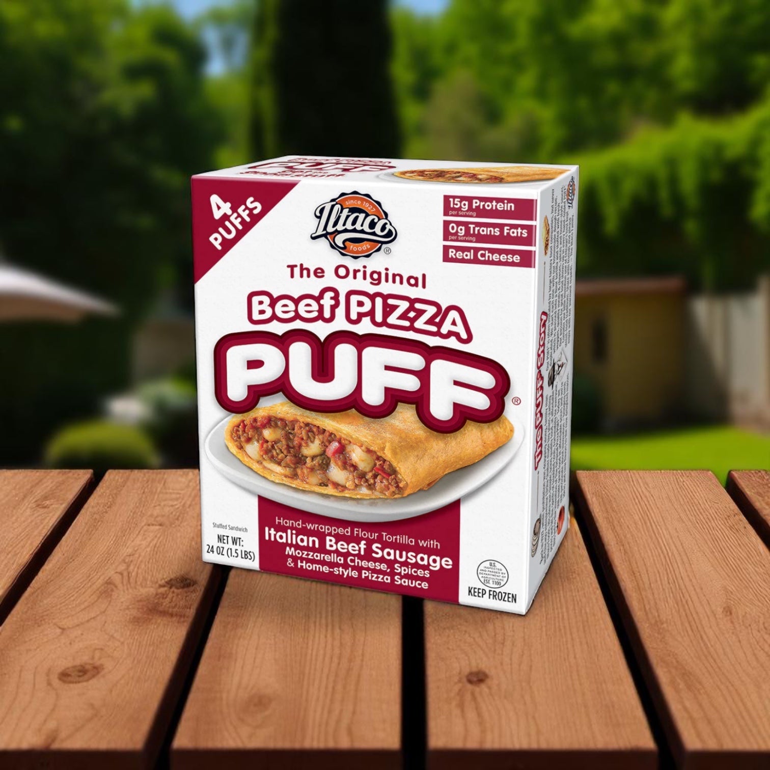 A box of The Original Pizza Puffs The Original Puff Beef Pizza (2 Count, 24 oz), featuring Italian beef sausage, mozzarella cheese, spices, and pizza sauce—a classic Chicago snack—sits on a wooden surface outdoors.