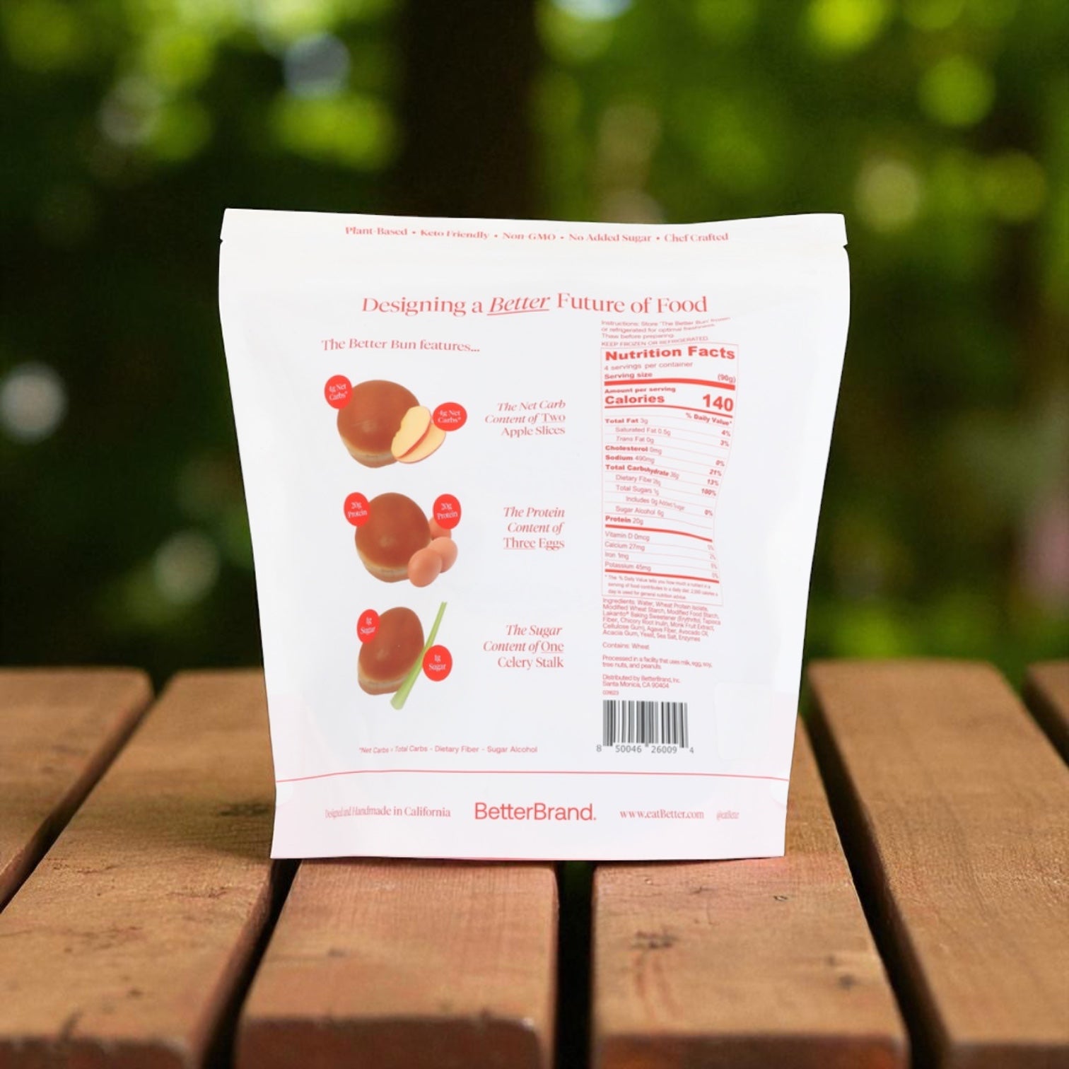 A bag of BetterBrand, The Better Bun – Brioche Style (4 Bag, 16 Buns) sits outdoors on a wooden surface, showing nutritional info and features on the package's back. In stock and ready to ship from BetterBrand!.