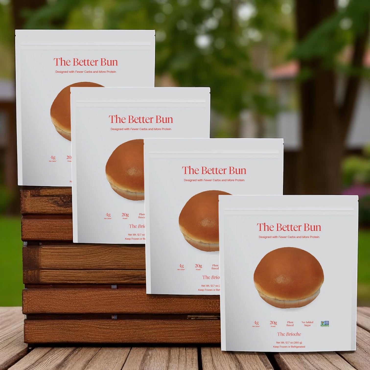 Four packs of BetterBrand The Better Bun – Brioche Style (16 low-carb buns) are displayed in a row on stacked wooden crates, with a blurred outdoor background. In stock and ready to ship!.