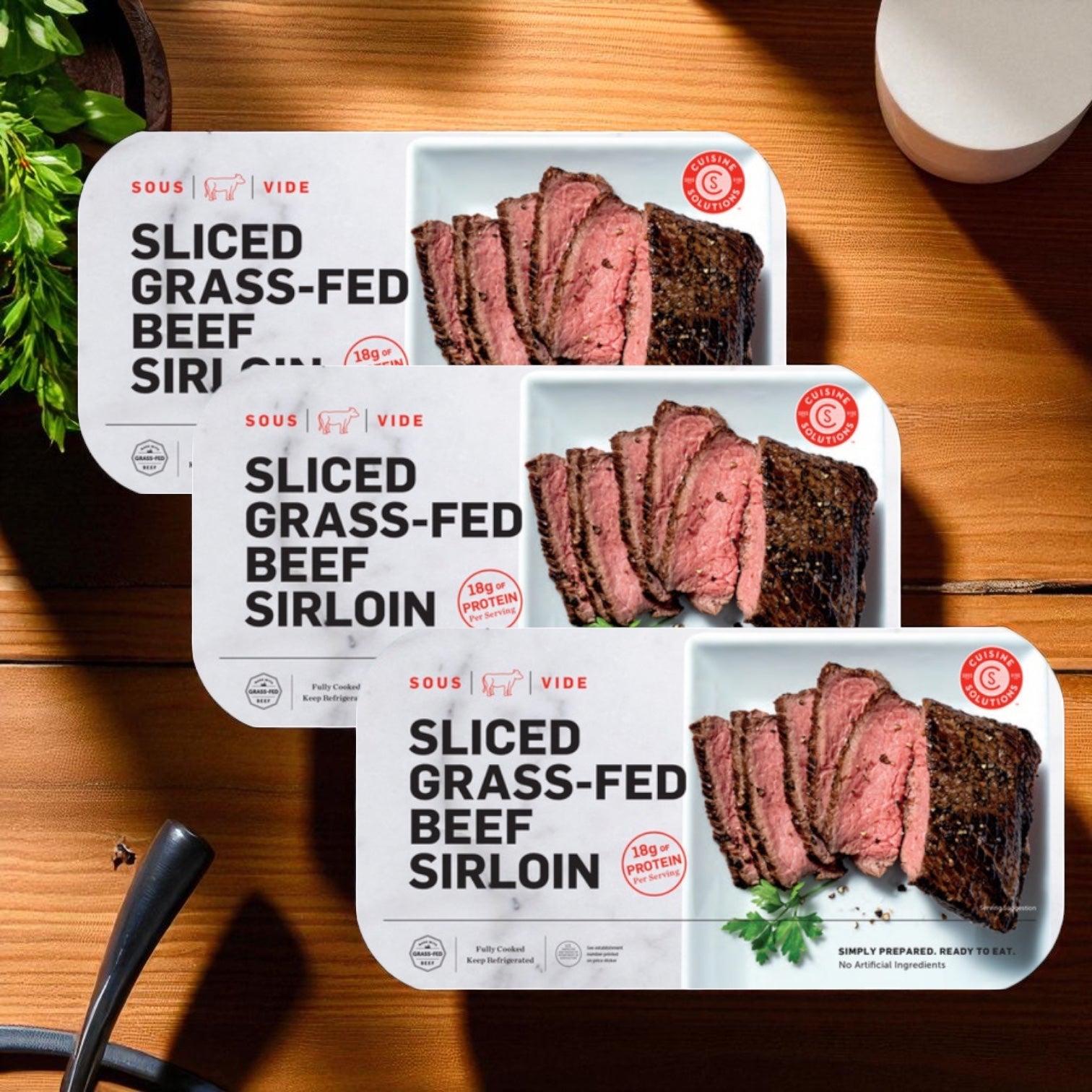 Cuisine Solutions Sliced Grass-Fed Beef Sirloin, 3-count, is fully cooked for convenience; each package highlights protein content and displays an image of sous-vide beef sirloin arranged on a wooden surface.