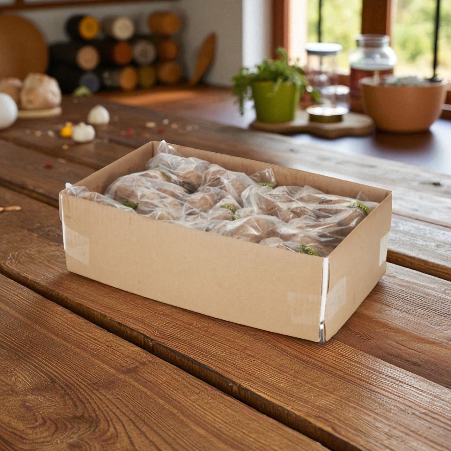 A cardboard box with vegetables in plastic bags sits on a wooden table alongside Sysco Fontanini Italian Beef Pork Meatball Fully Cooked 2 Ounce (5 lb, 2 count), with herbs and kitchen items in the background.