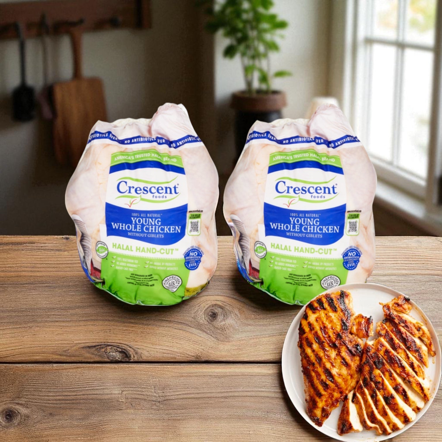 Two packages of Crescent Foods Halal Hand-Cut Young Whole Chicken Without Giblets, 3 lbs, 2 ct, sit beside grilled chicken breasts on a table with kitchen utensils and a window in the background—enjoy quality hand-cut halal chicken every meal.