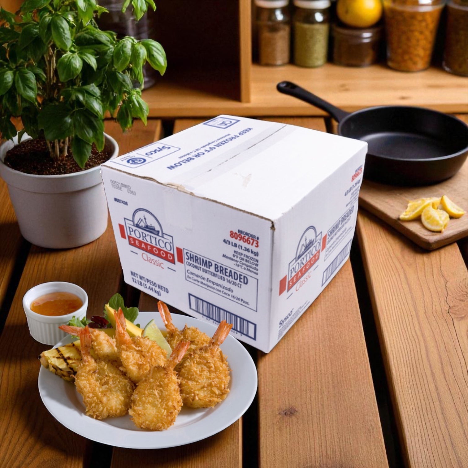 A plate of crispy coconut shrimp with dipping sauce sits beside a box labeled "Sysco Shrimp Breaded Coconut Butterfly 3 lb - 4 Count" on a wooden table, with a potted plant and kitchen items in the background.