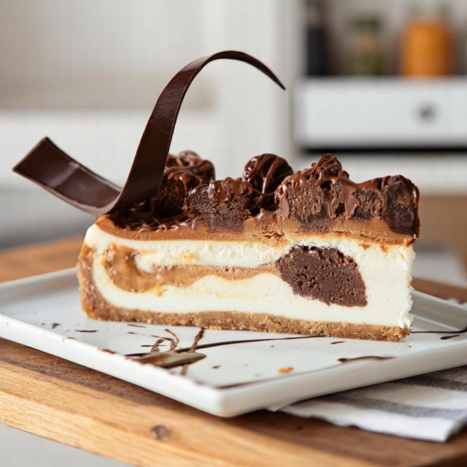 A slice of Sweet Street Caramel Cheesecake Brownie combines rich chocolate, creamy caramel, and decorative chocolate pieces—a gourmet dessert from Sweet Street’s 2-cake, pre-sliced (14 slices each) pack.