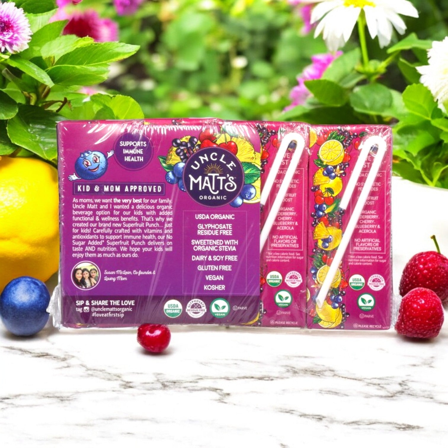 Three 6.75 fl oz boxes of Uncle Matt's Organic Superfruit Punch, with USDA Organic certification, sit among berries. The packaging highlights antioxidants and vitamins; it's gluten-free, vegan, and has no sugar added.