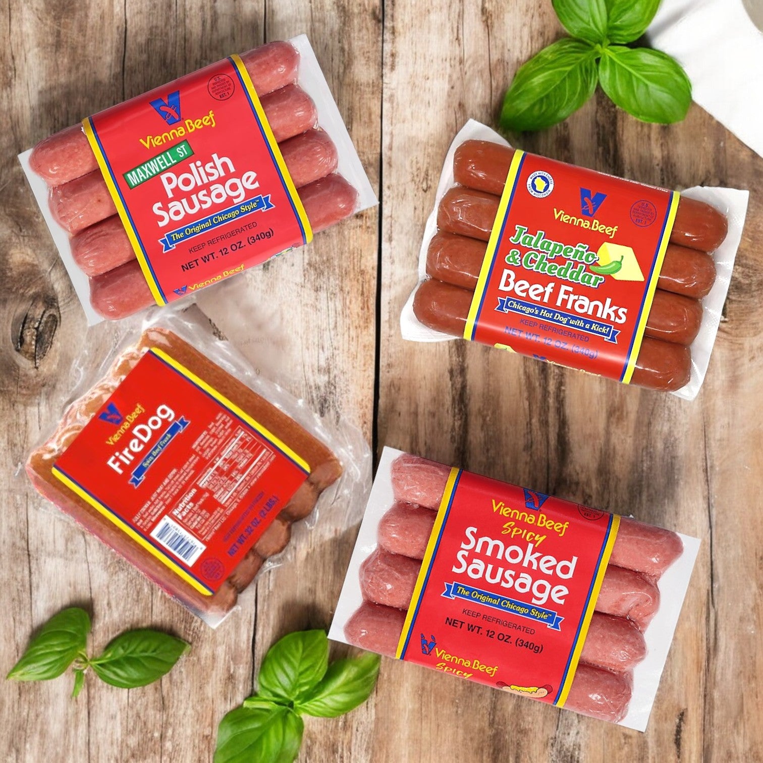 The Vienna Beef Variety Pack—A Classic Selection of Chicago’s Finest Sausages & Poppy Seed Buns!—is displayed on a wooden surface with basil leaves scattered around, showcasing an assortment from the renowned Vienna Beef brand.