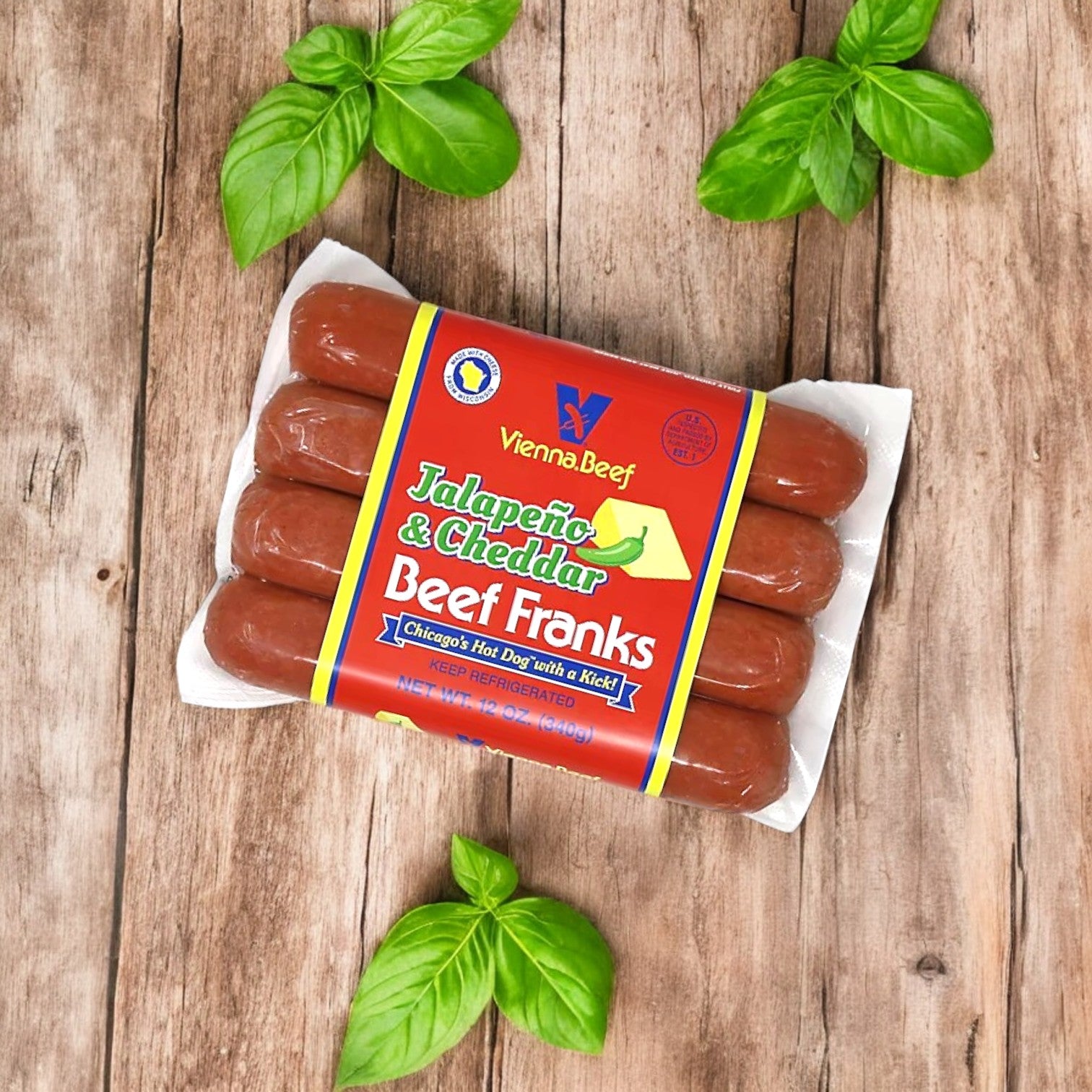 A Vienna Beef Variety Pack – A Classic Selection of Chicago’s Finest Sausages & Poppy Seed Buns! is placed on a wooden surface, surrounded by fresh basil leaves.