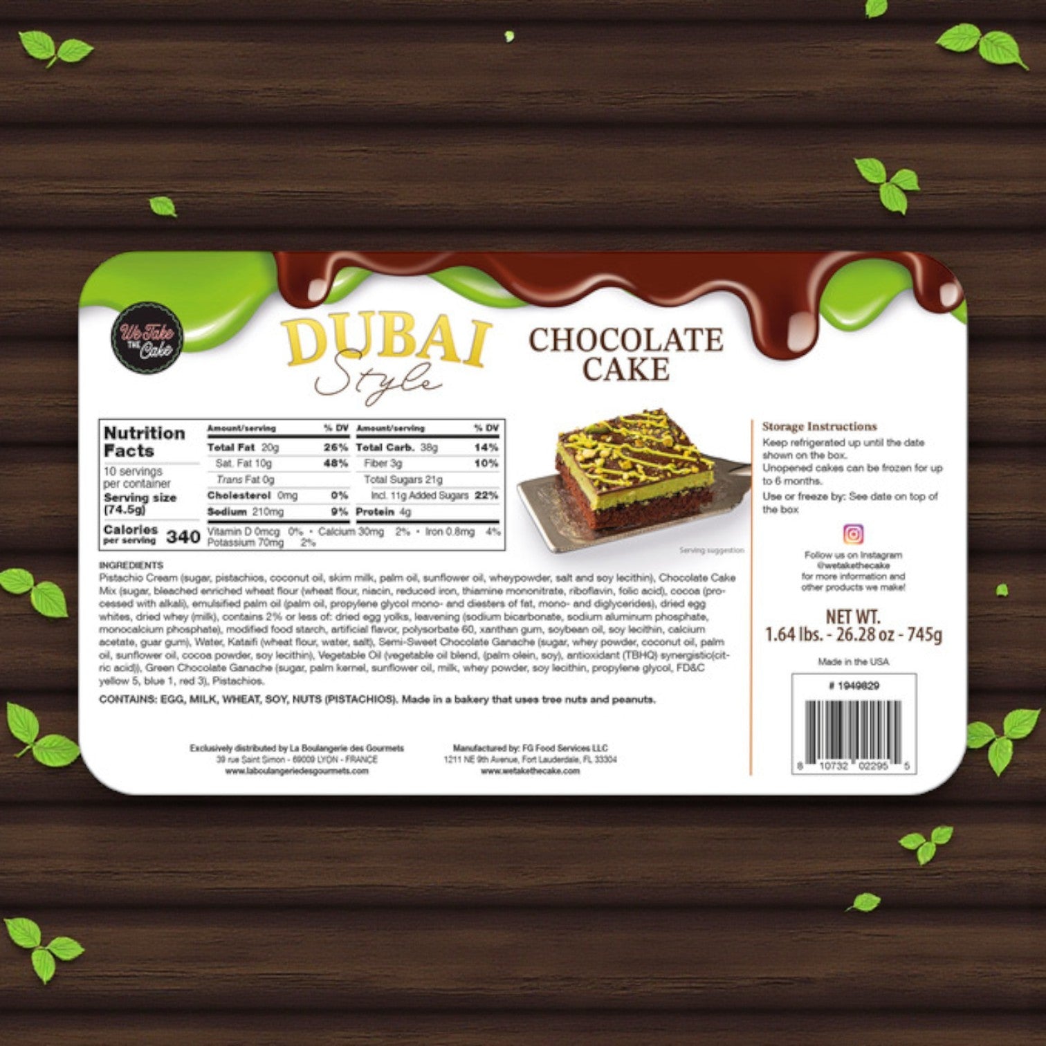 Label for We Take The Cake – Dubai-Style Chocolate Cake, 26.28 oz by We Take The Cake, featuring nutrition facts, ingredients, storage instructions, and weight on a wooden background with scattered green leaves.