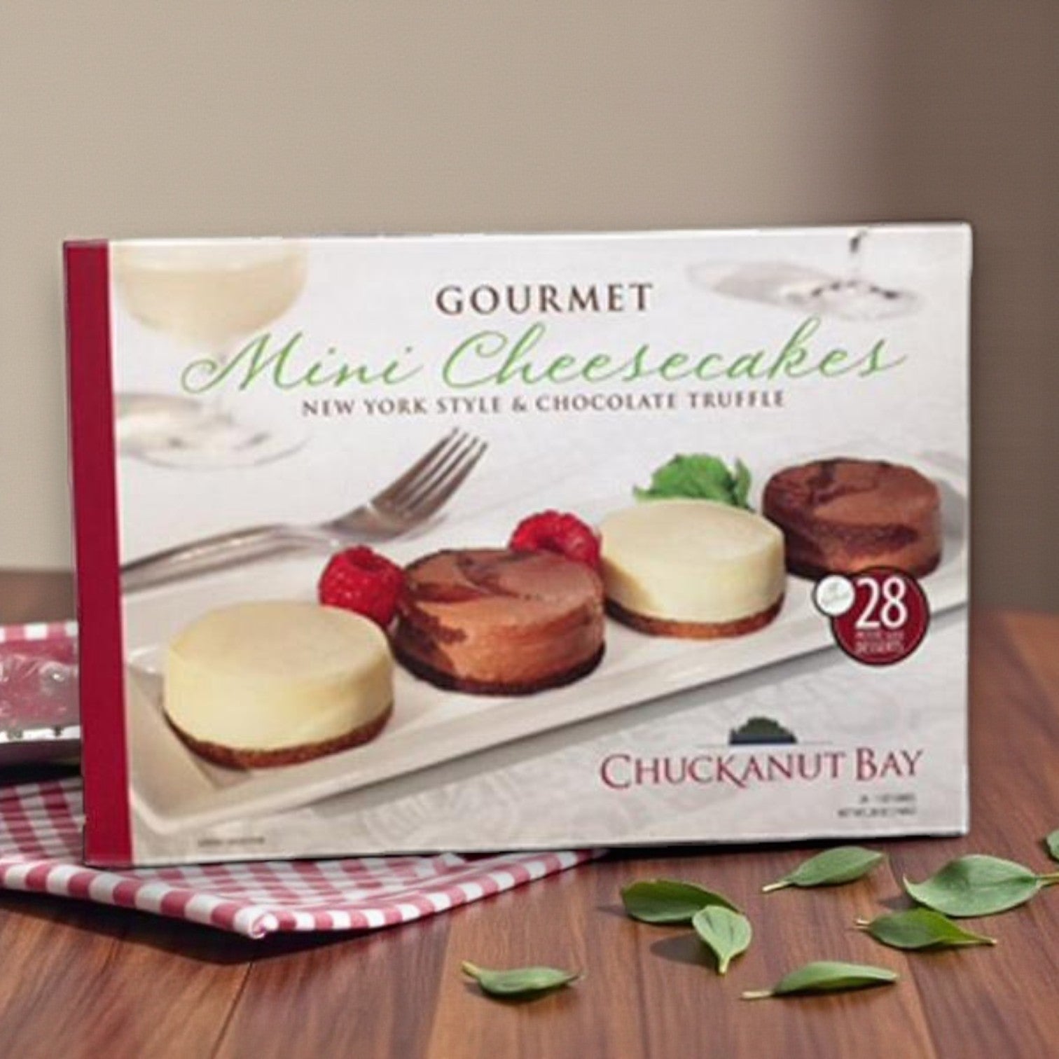 A box of Chuckanut Bay Assorted Mini Cheesecakes – 28 Count, featuring New York style and chocolate truffle cheesecakes, beautifully presented on a white plate.