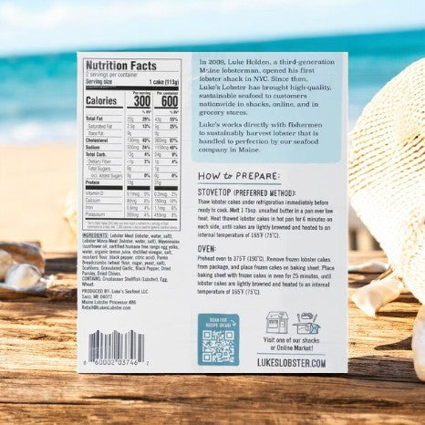Back of a Luke's Organic Lobster Cakes, Garlic & Herb-1 Count package by Luke's, showing nutrition facts, cooking instructions, organic ingredients story, and barcode on a wooden surface near the beach.