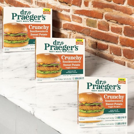 Three boxes of Dr. Praeger's Crunchy Southwestern Sweet Potato Veggie Burgers are displayed on a white marble surface against a brick wall. These gluten-free, plant-based burgers, from Dr. Praegers, are packed with southwestern flavor and ideal for those seeking tasty vegan options.