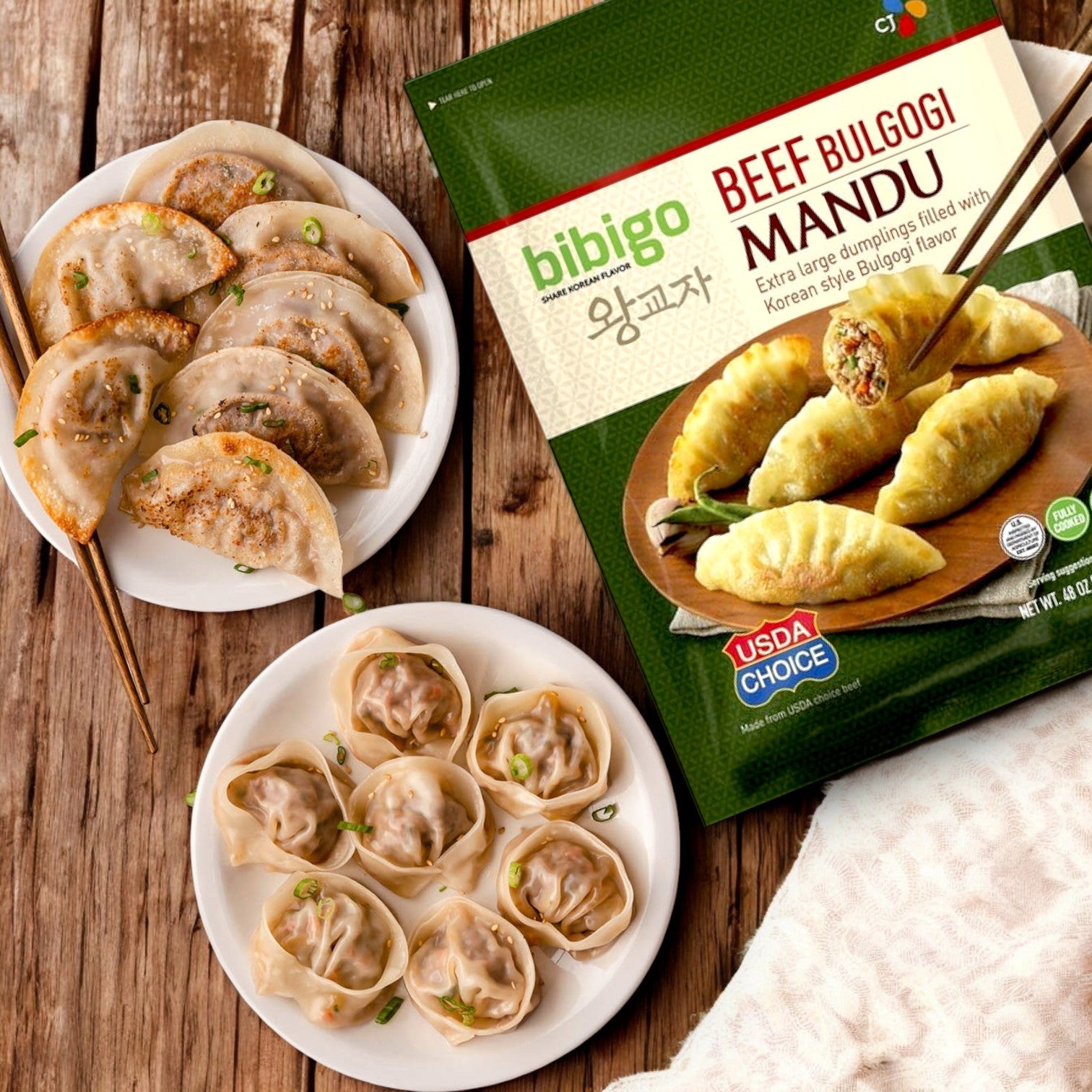Three plates of cooked dumplings sit next to a 9 lb package of Bibigo Beef Bulgogi Mandu Dumplings, highlighting the savory taste of Bibigo’s Korean cuisine on a wooden surface.