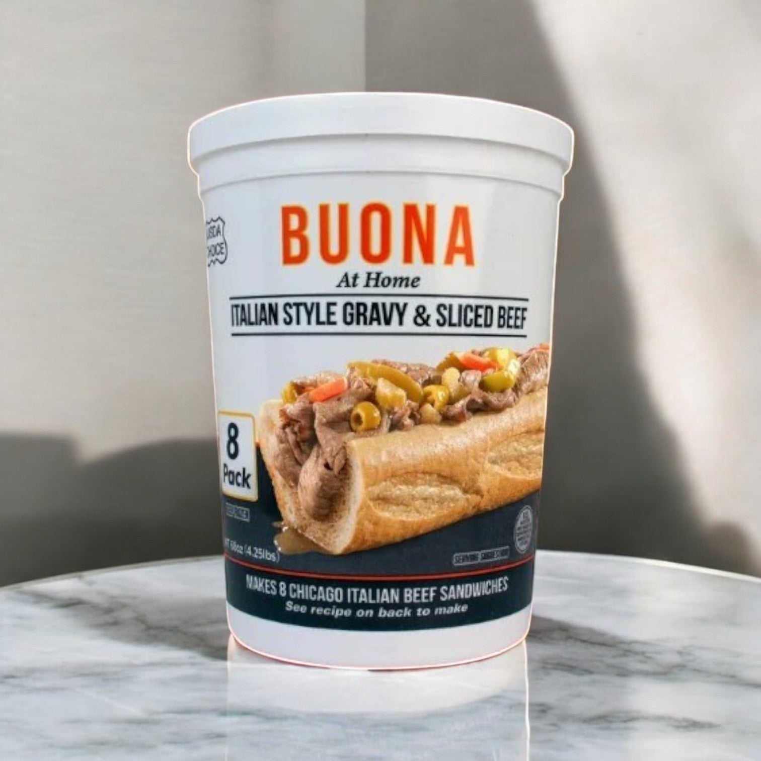 An 8-pack of Buona Gravy & Sliced Beef, Italian Style, is on the table, perfect for making classic Chicago Italian beef sandwiches with its flavorful gravy.
