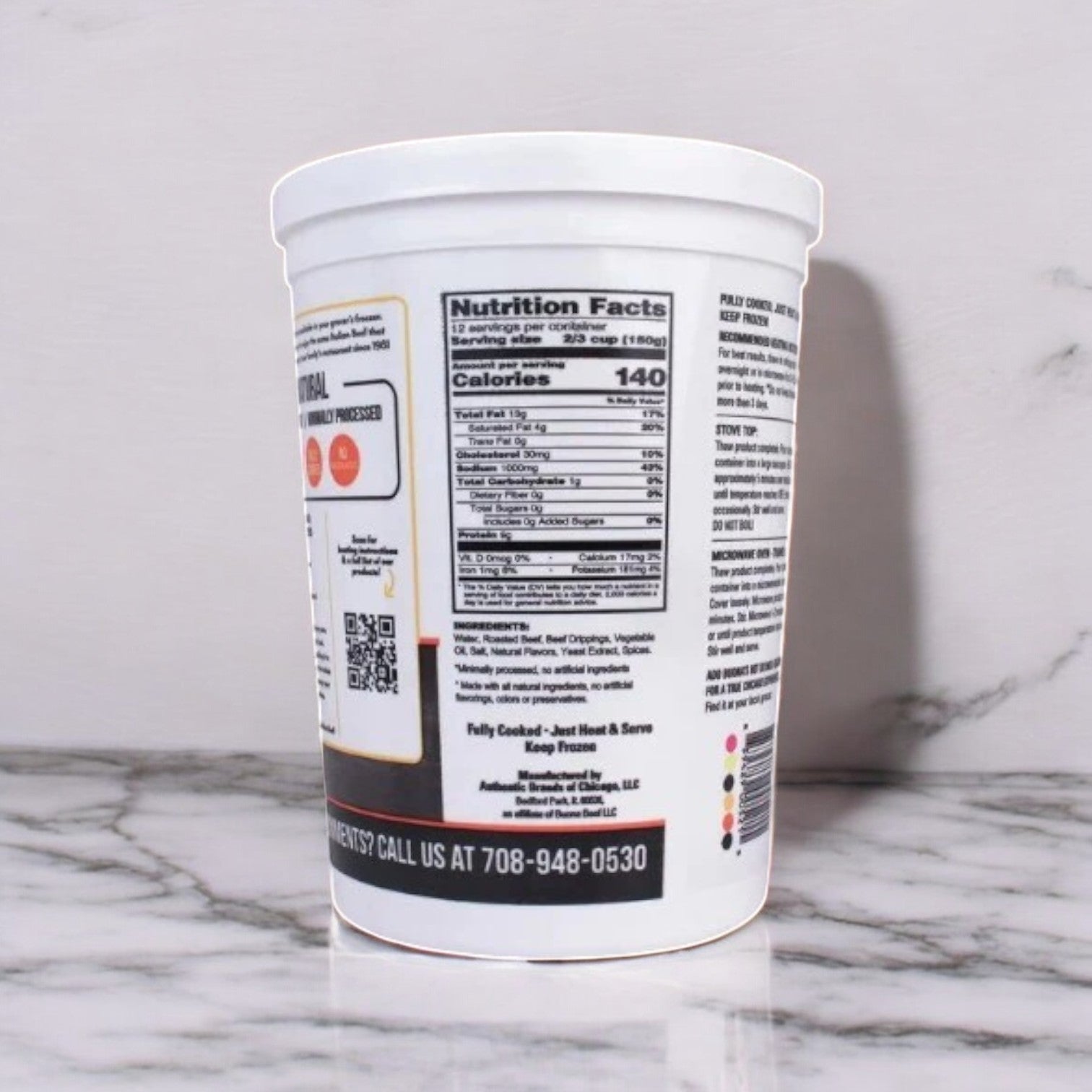 A Buona Gravy & Sliced Beef, Italian Style cup, marked with its nutrition facts and contact number, sits on a marble surface.