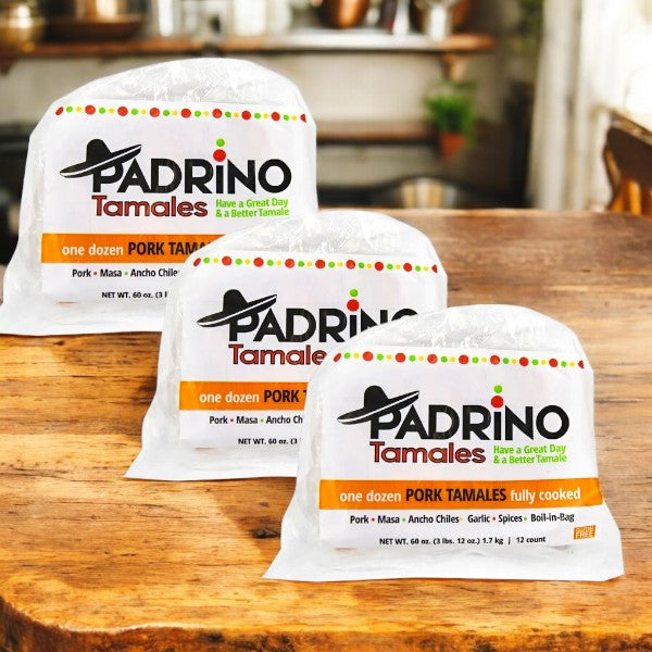 Three packs of Padrino Tamales Pork Tamales (60 oz, 3 Count) by Padrino Tamales are shown on a wooden surface with a blurred kitchen background—ideal for foodservice distributors wanting authentic flavor.