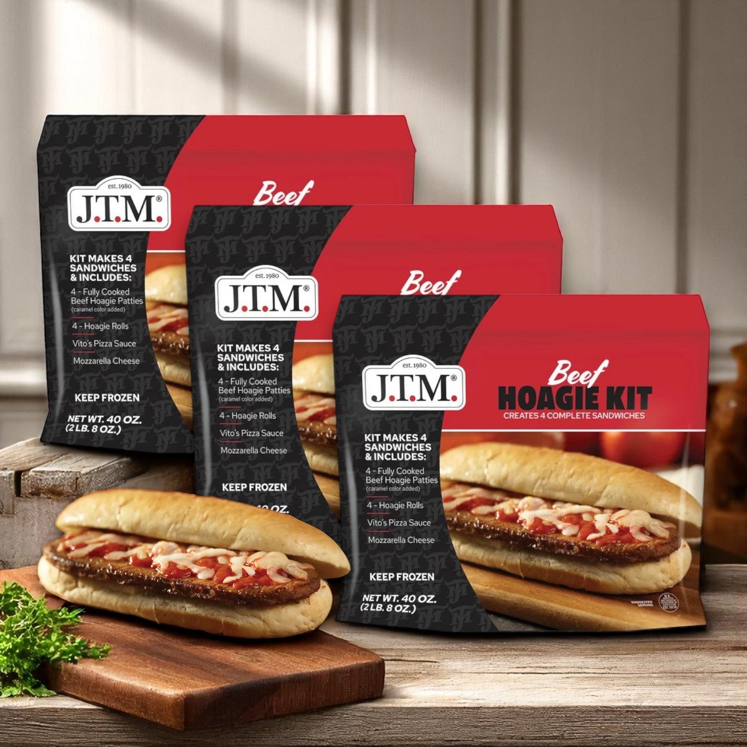 Three boxes of J.T.M Beef Hoagie Kit – 3 Packs (2 lbs Each), Makes 12 Complete Sandwiches, are displayed on a wooden counter, each showing Philly-Style hoagies made with fully cooked seasoned beef on the packaging.