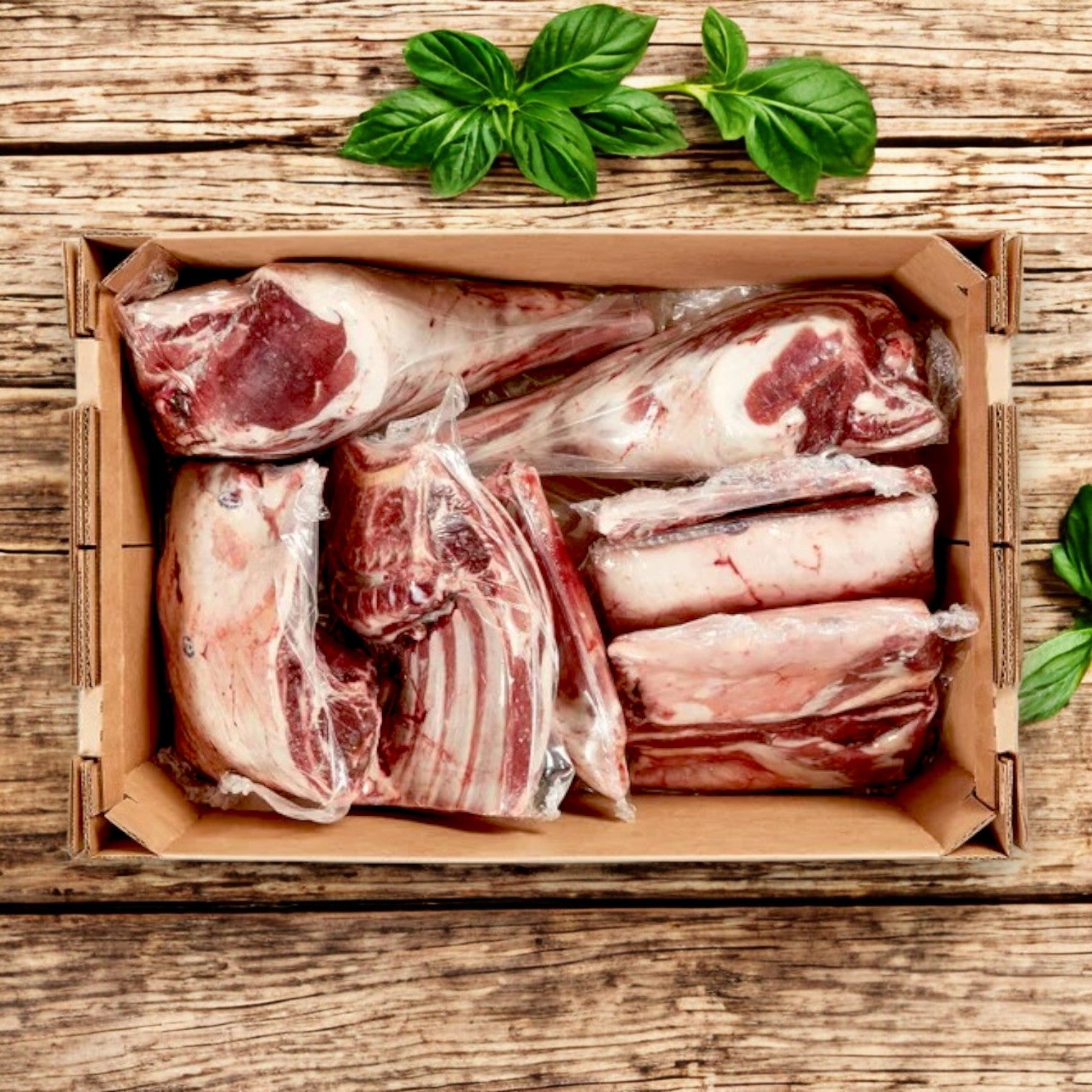 A cardboard box of New Zealand Spring Lamb Halal Lamb Carcass, 8-Way Cut (28 lb avg wt), sits on a wooden surface with fresh basil leaves nearby.