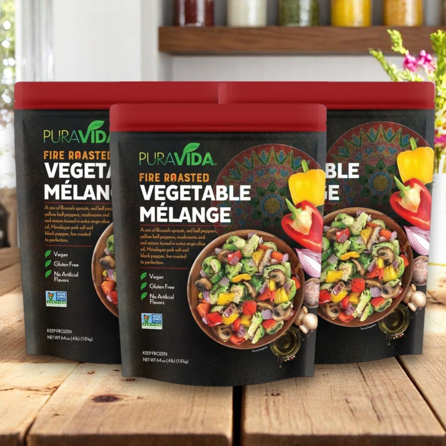 Three packs of Pura Vidaa Fire-Roasted Vegetable Mélange (64 oz each) are displayed on a wooden surface with a kitchen background.