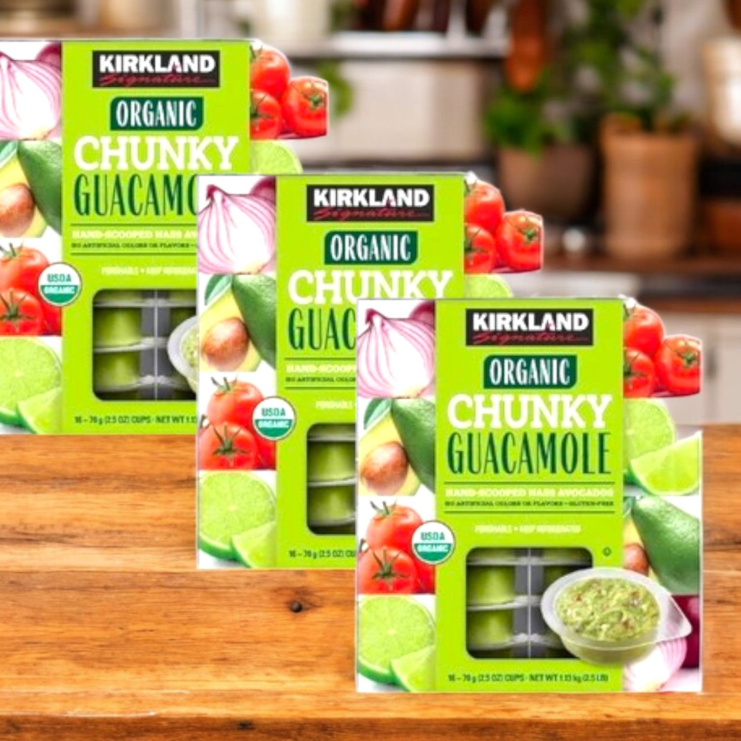 Three Kirkland Signature Organic Chunky Guacamole cases, made from ripe avocados, are displayed on a wooden surface, with kitchen items blurred in the background.