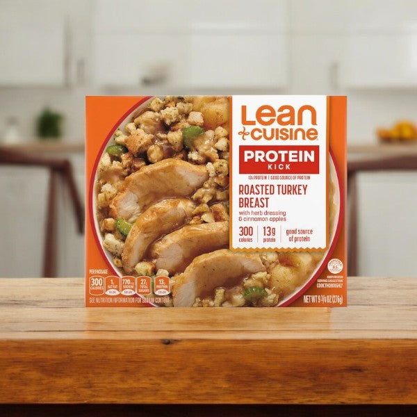 A Lean Cuisine Protein Kick Frozen Roasted Turkey Breast-1 Count meal from Lean Cuisine sits on a wooden table, with a softly blurred kitchen in the background.