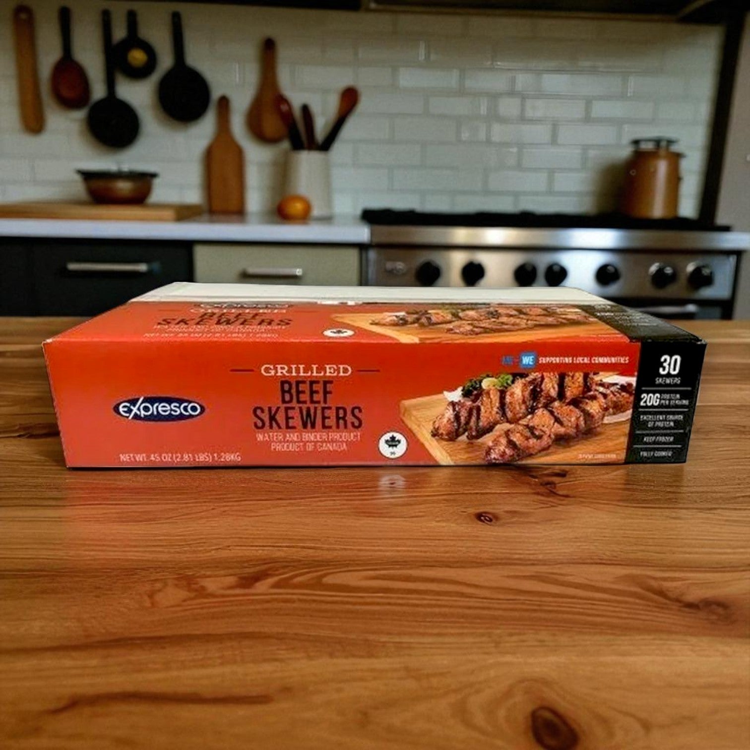 A box of Gordon Choice Expresco Grilled Beef Skewers – 30 Count sits on a wooden kitchen counter, with a stove and utensils visible in the background.