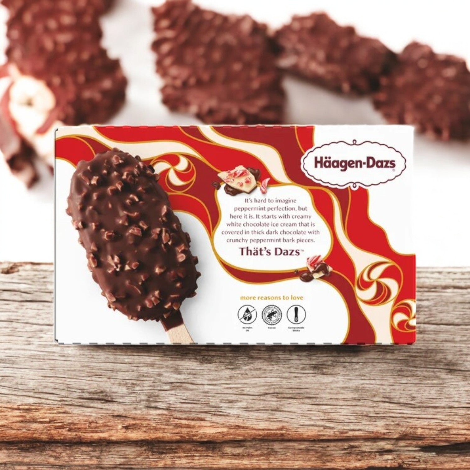 Haagen-Dazs Peppermint Bark Ice Cream Bars, presented in a 3 oz size and available as a 15-count case, are elegantly arranged on a wooden surface. A close-up highlights the intricate swirls and imagery on the packaging of these premium bars crafted by Haagan-Dazs.
