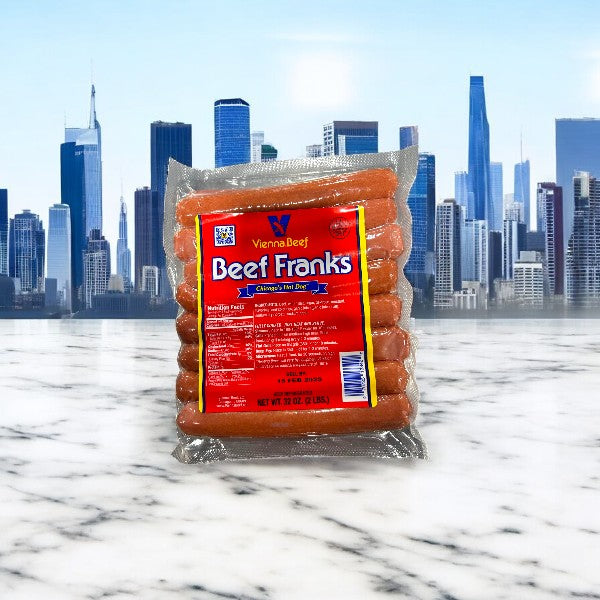 Four 32oz packs of Vienna Beef Franks (64 total) are displayed on a marble surface, with a city skyline in the background.