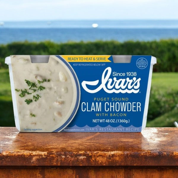 A box of Ivar's Clam Chowder With Bacon sits on a ledge, the creamy chowder enhancing the ocean view in the background.