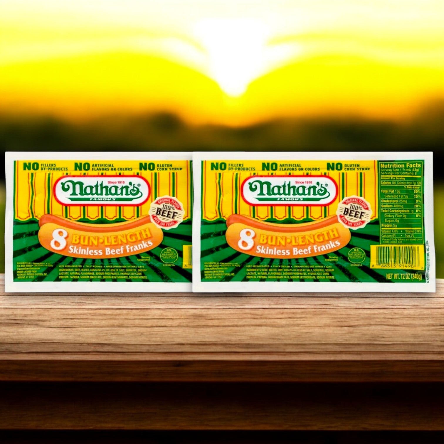 Nathan’s Famous Hot Dog & Fries Bundle includes 16 hot dogs, 16 buns, and 2 bags of fries—everything you need for a classic meal, all displayed on a wooden surface with a vibrant sunset in the background.