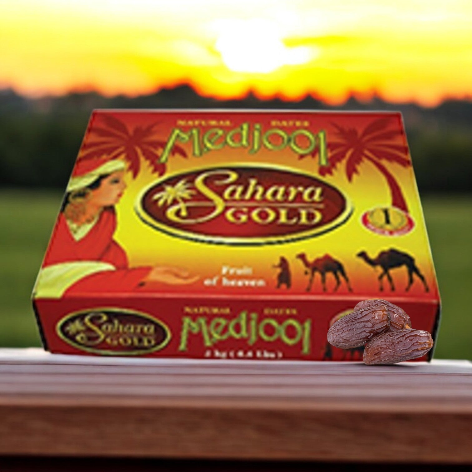 A box of Easy Lunches Golden Foods - Extra Large Medjool Dates (4.4 lbs) sits on a wooden surface, their natural sweetness enhanced by a blurred sunset landscape in the background.