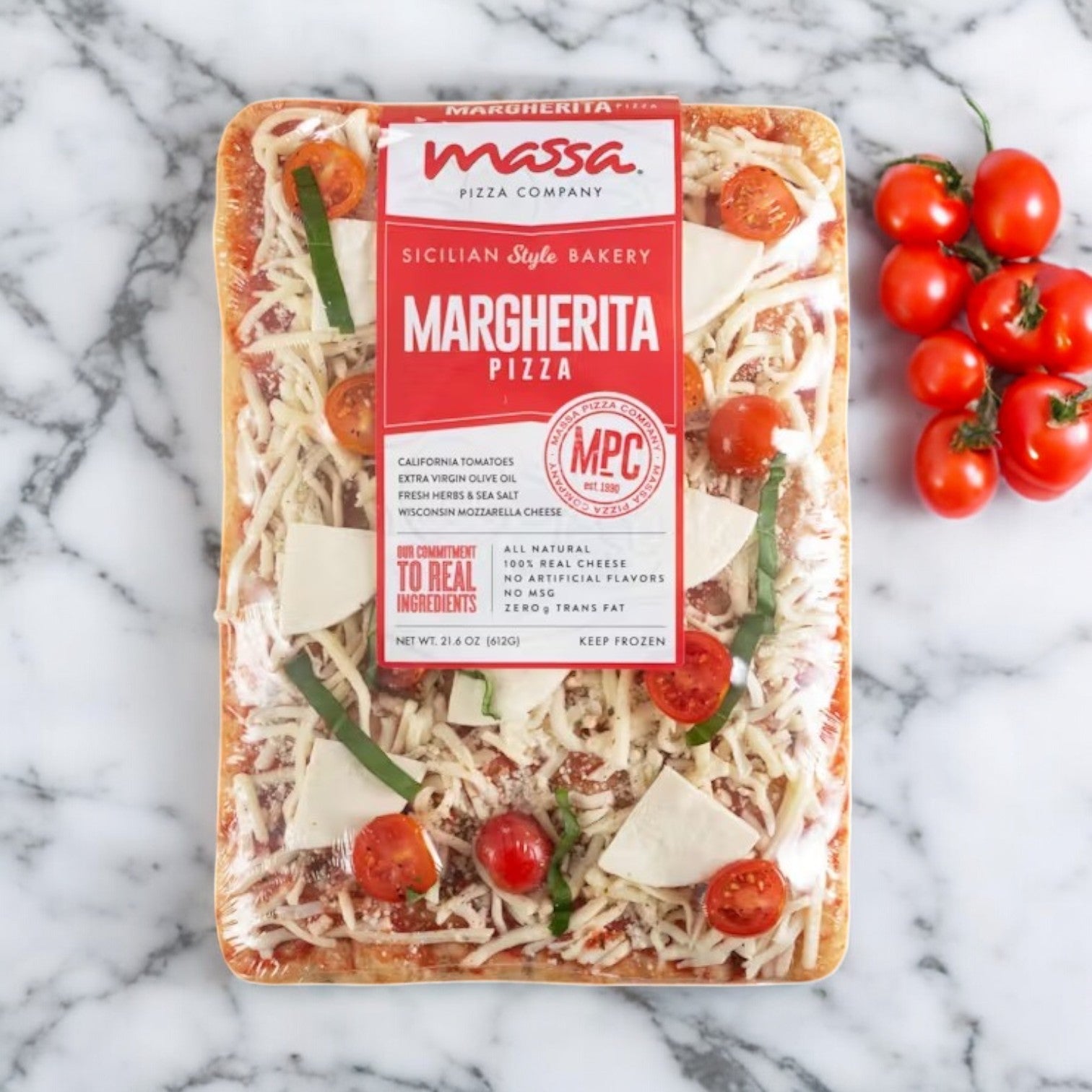 A Massa Pizza Co. 3 Pack Combo! from Massa Pizza, featuring an artisan bakery crust, is elegantly displayed on a marble surface alongside fresh cherry tomatoes and basil.