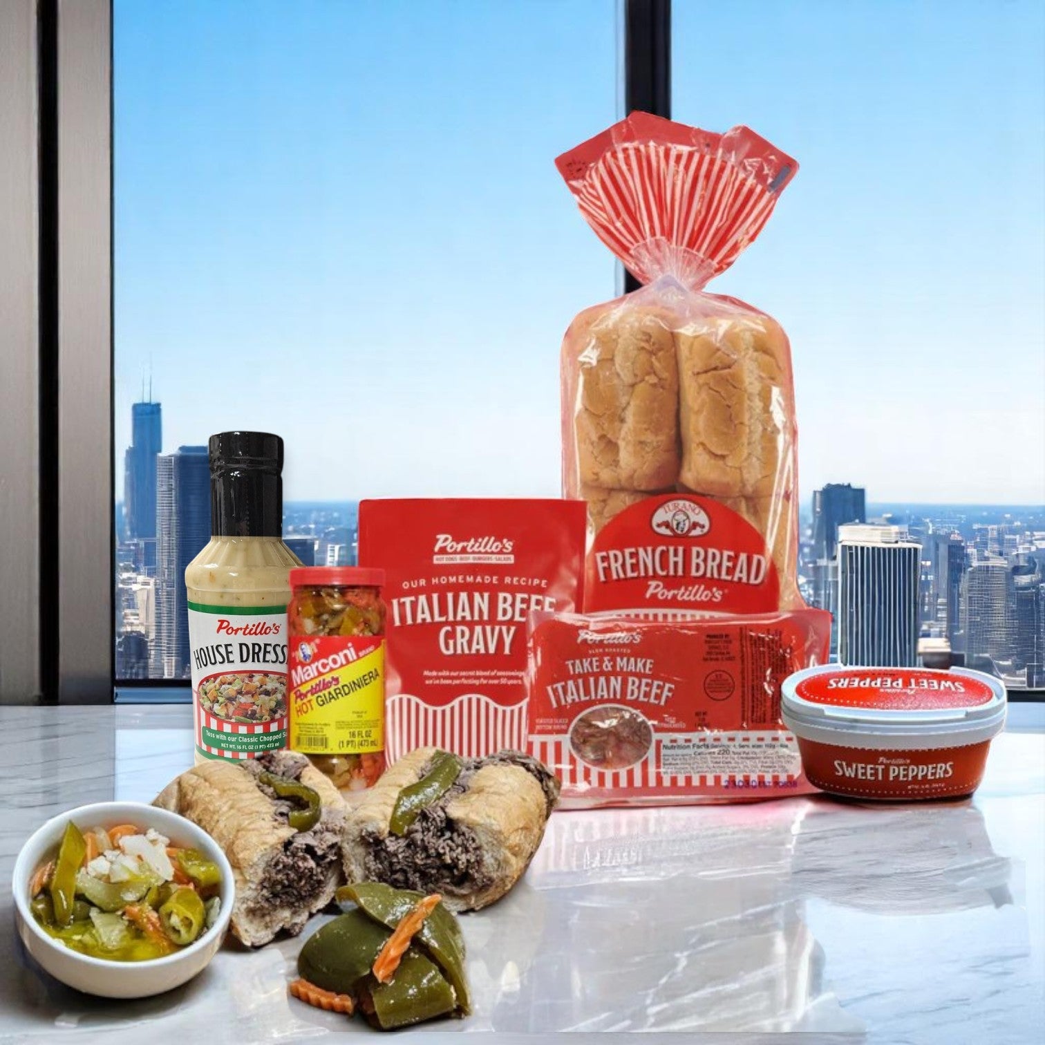 A Portillo’s Italian Beef Bundle from Portillo's, featuring bread, beef, signature gravy, sweet peppers, hot giardiniera, and Portillo’s House Dressing, is displayed on a marble surface with a city skyline in the background.
