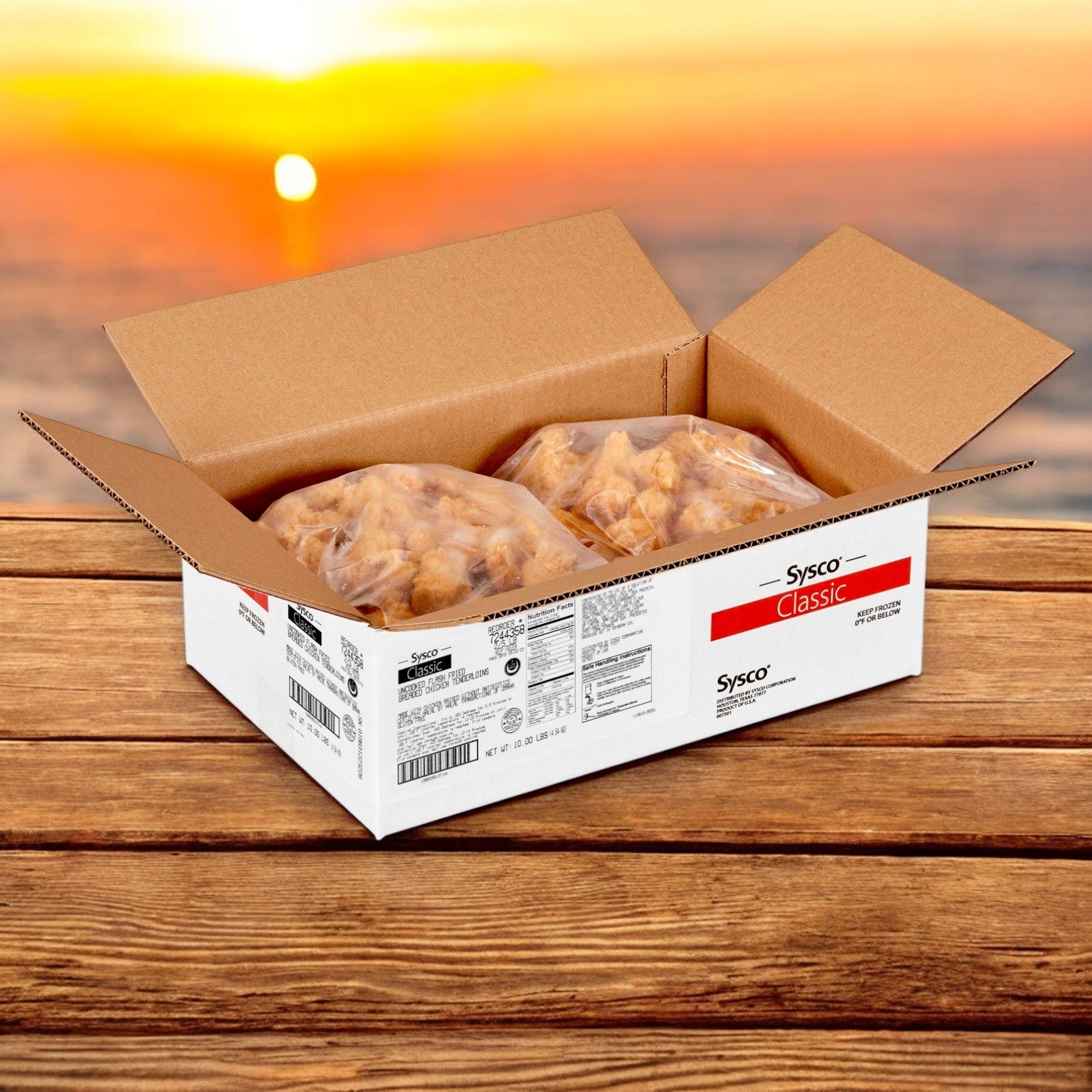 An open Sysco Classic box of Halal Chicken Tender Breaded Gluten-Free Halal (2/5 lb) sits on a wooden surface, with two bags visible and a sunset over water in the background.