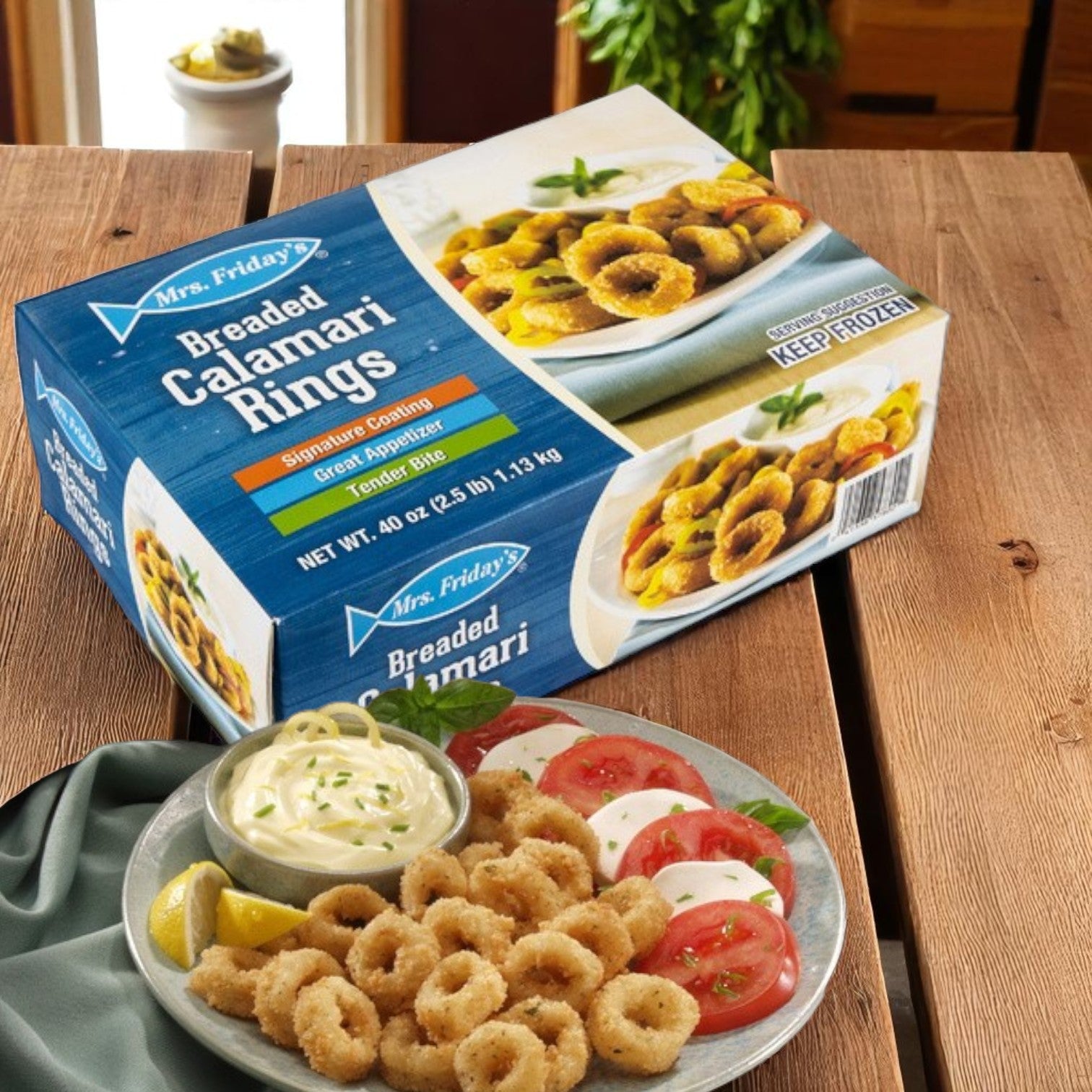 A box of Mrs. Friday’s® Breaded Calamari Rings – 4 × 2Ibs-8Ibs from Mrs. Friday's is on a wooden table beside a plate of cooked seafood appetizers, tomato slices, and a cup of dipping sauce.