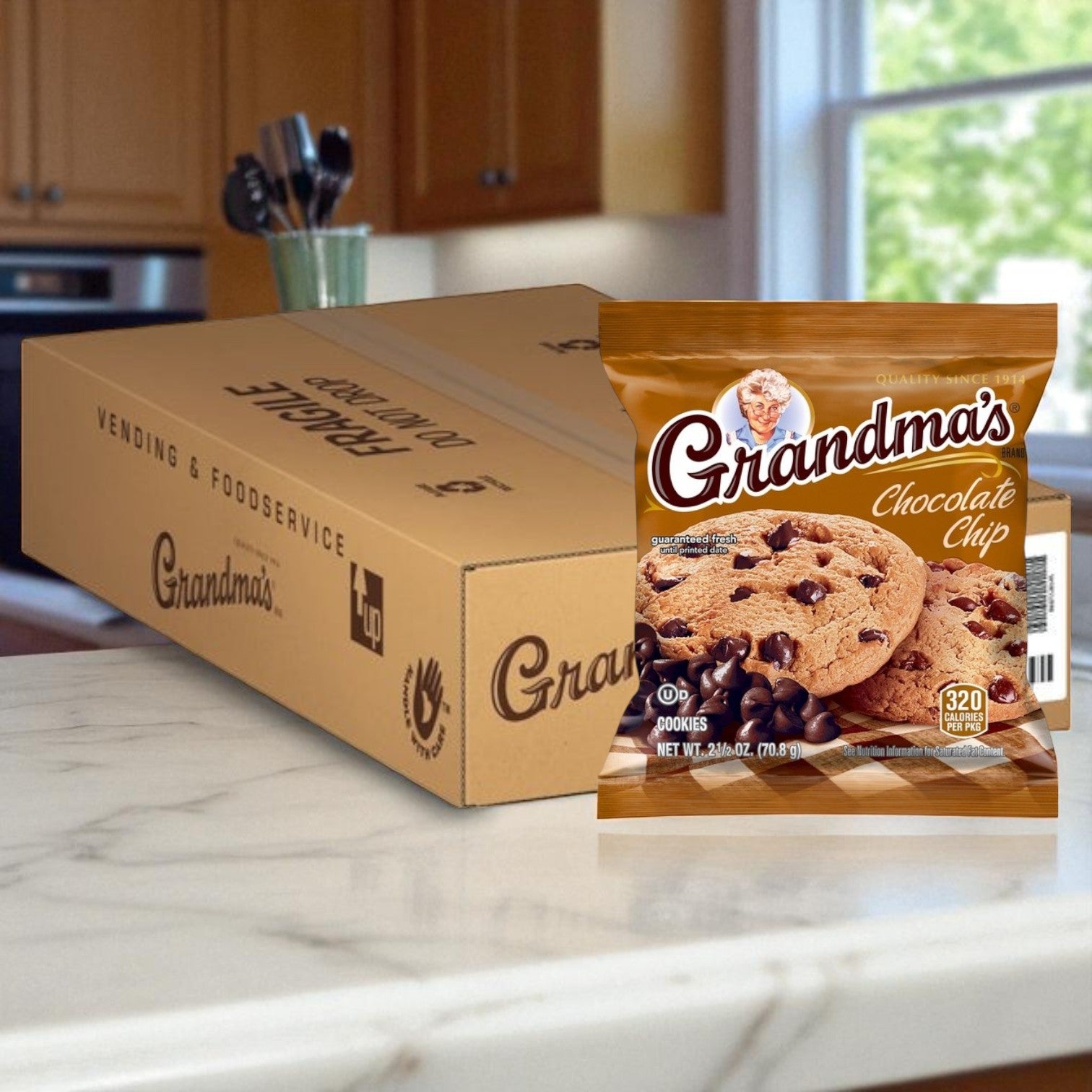 A box labeled "Grandma's" holds 60 individually wrapped 2.5 oz Grandma’s / Cadbury Chocolate Chip Cookies, with one cookie pack displayed on the kitchen counter for freshness and convenience.
