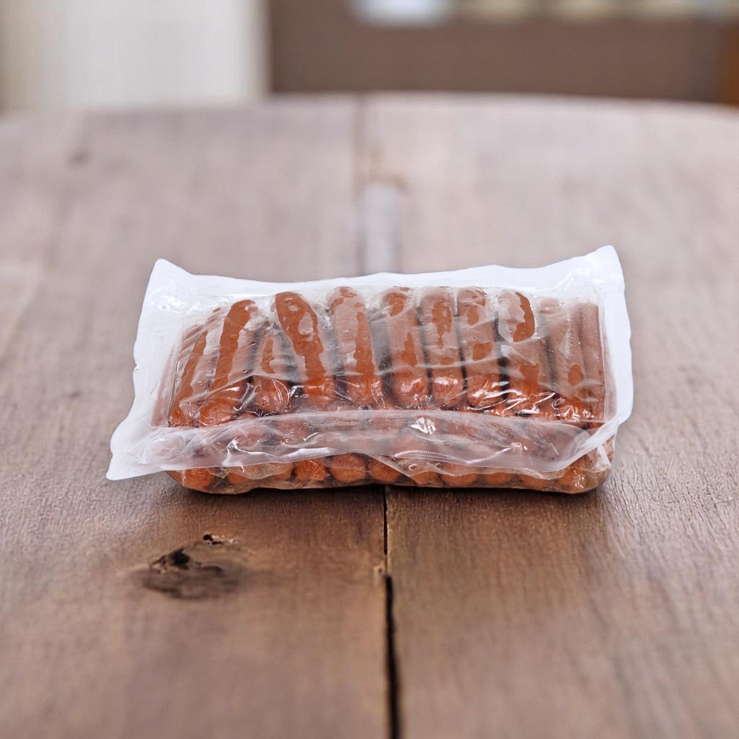 A sealed plastic package of Easy Lunches Eisenberg Mini Angus Beef Franks – 16/1 Size (4 Packs of 3 lbs Each) sits on a wooden table.