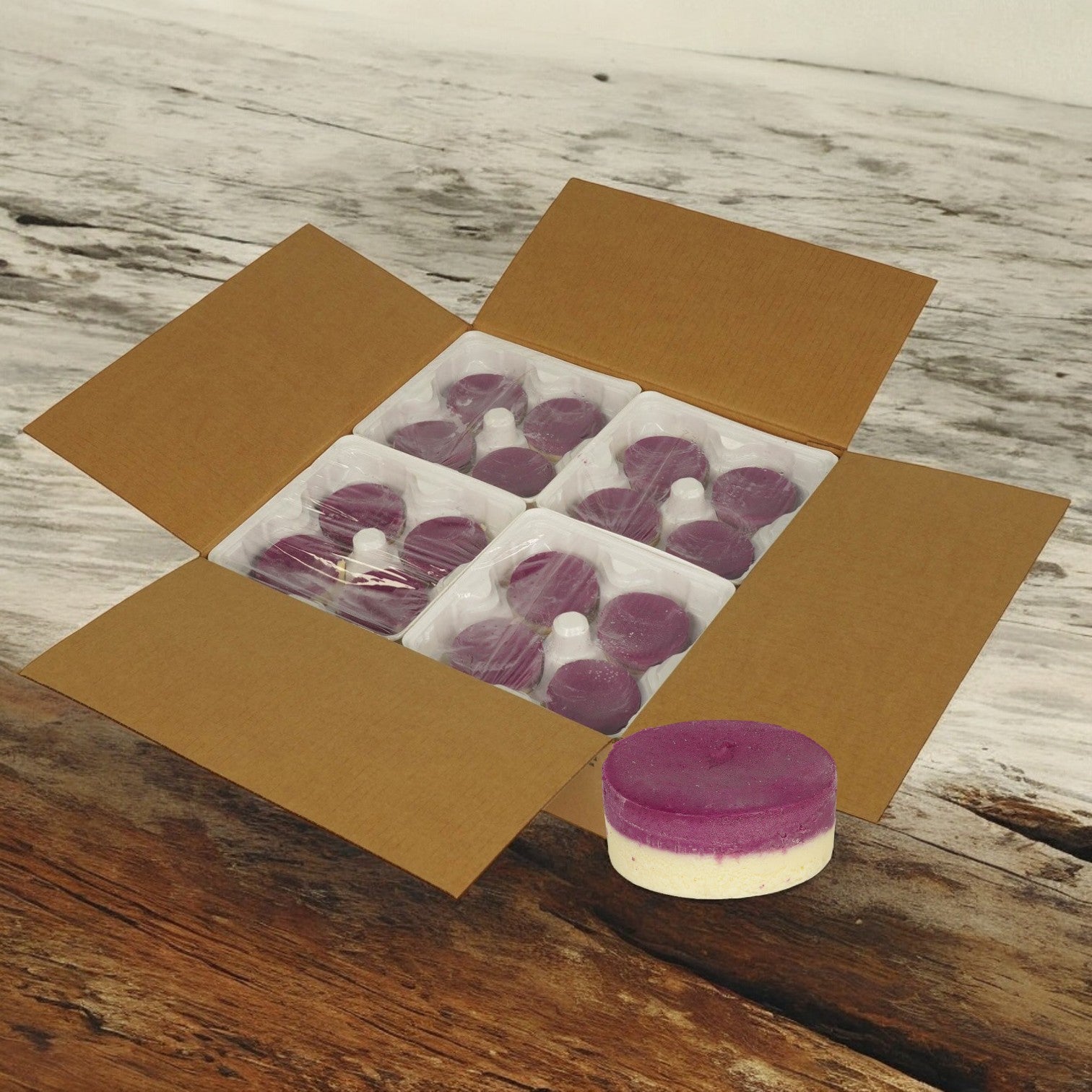 An open Sweet Street box holds 32 individually wrapped Ube Cheesecakes (4.03 oz each) in plastic trays, with one purple and white cheesecake placed on a wooden surface nearby. Please allow 2–3 extra days for processing before shipping.