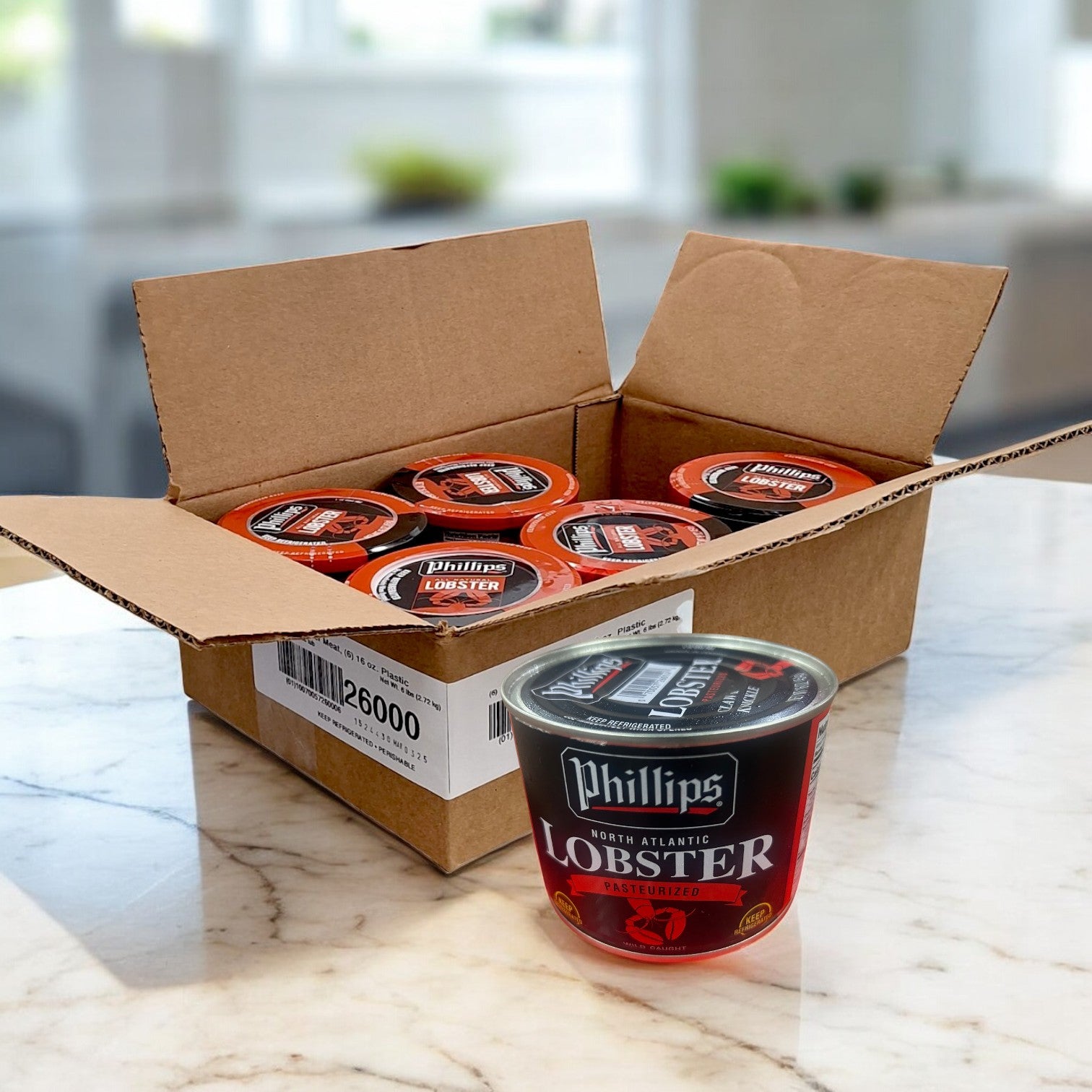 An open cardboard box with several Phillips Foods Lobster Meat – 16 Ounces (6/16 oz) containers on a marble countertop, with one ready-to-use container placed in front.