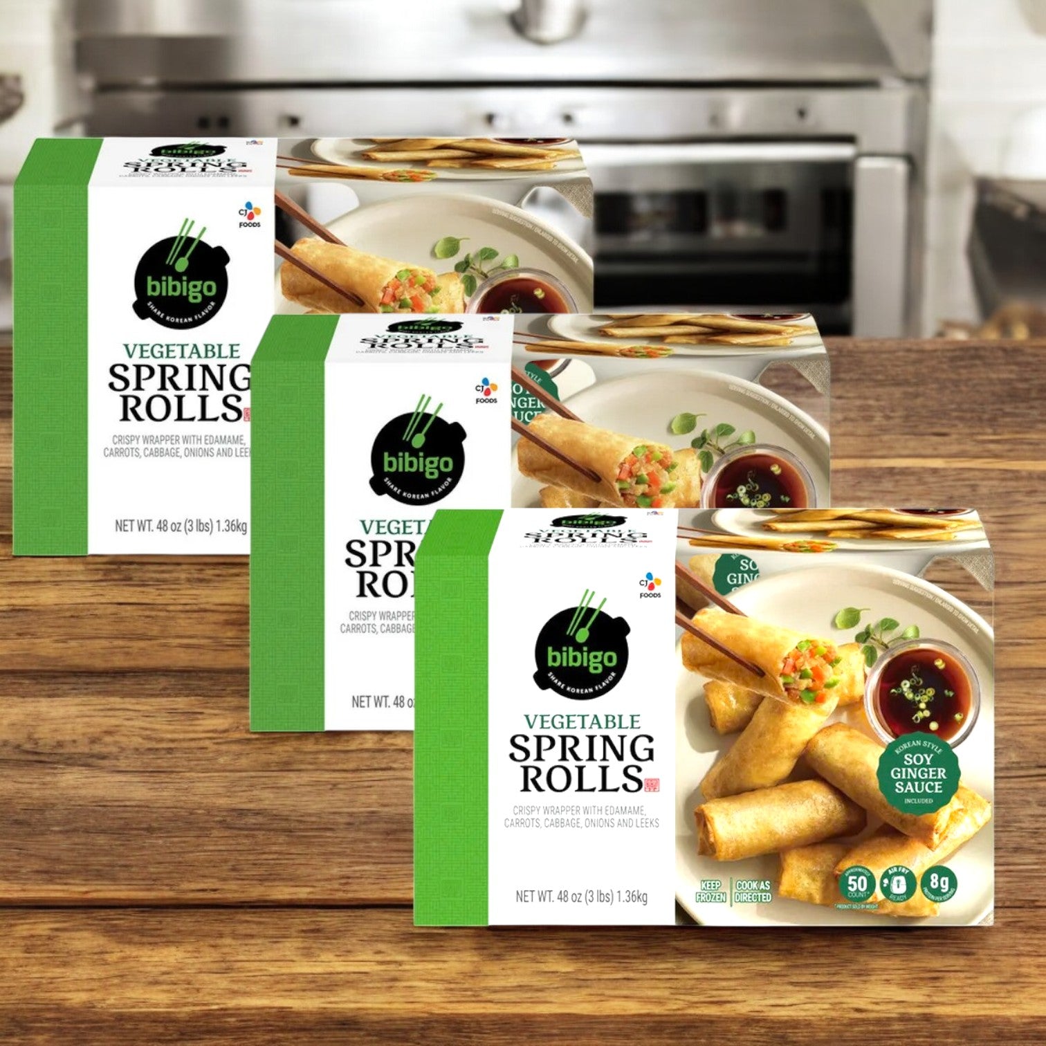 Three packs of Bibigo Vegetable Spring Rolls, a tasty vegetarian option by Bibigo, are displayed on a wooden kitchen surface.