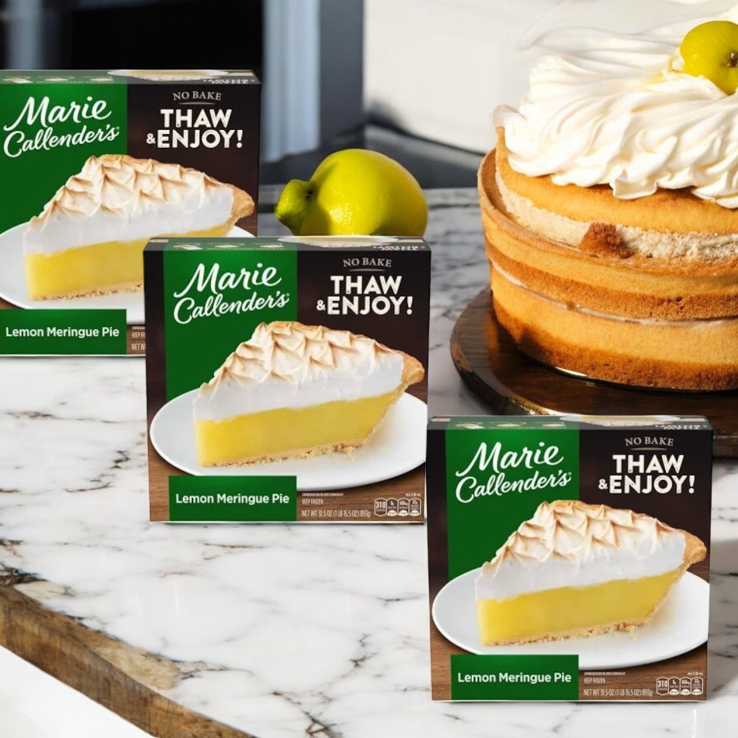 Three boxes of Marie Callender's Lemon Meringue Pie Frozen Dessert, each 31.5 oz, are displayed on a marble surface next to a whole frozen dessert topped with meringue.