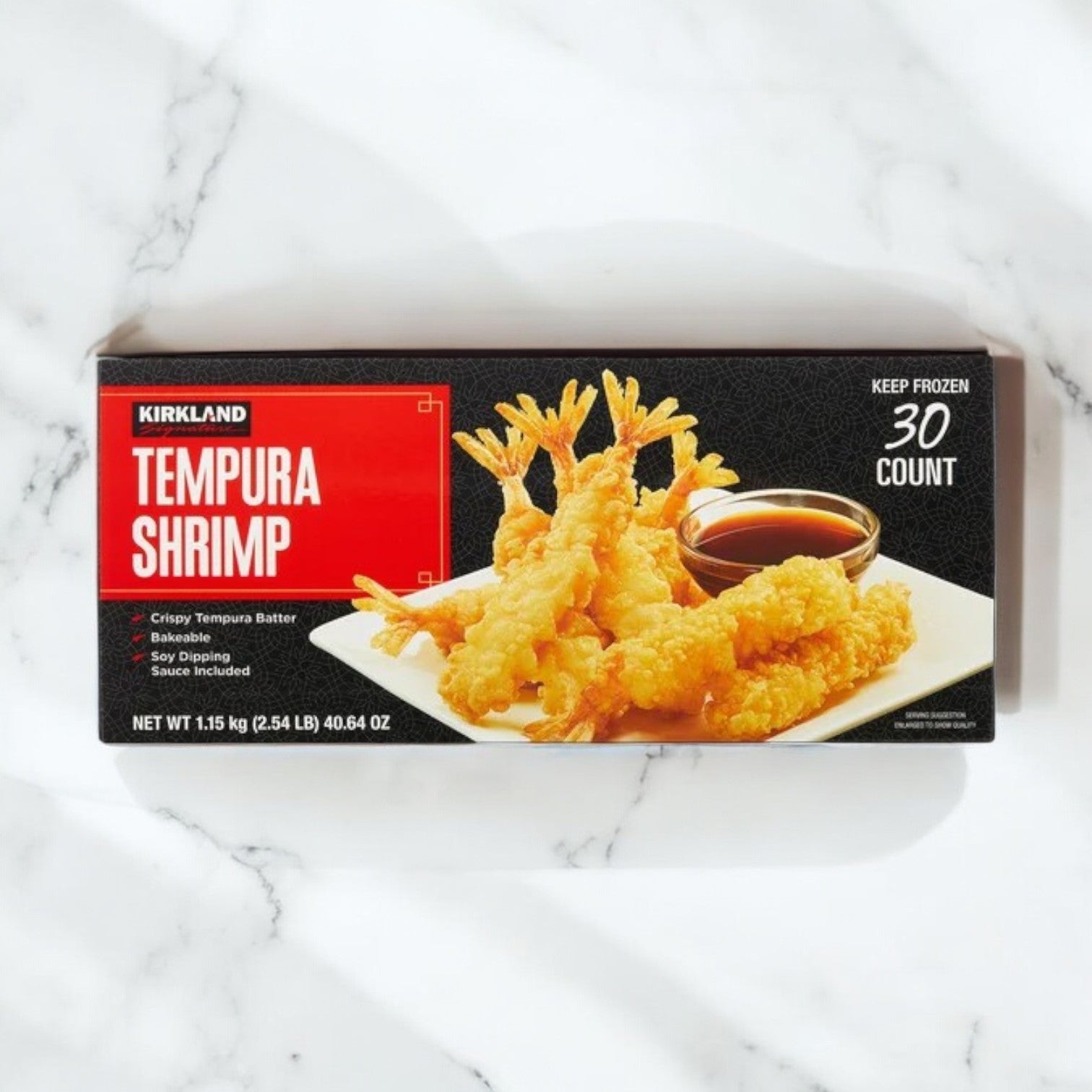 A 2.35 lb box of Kirkland Signature Tempura Shrimp (30-count) is shown plated with dipping sauce on a white marble surface.