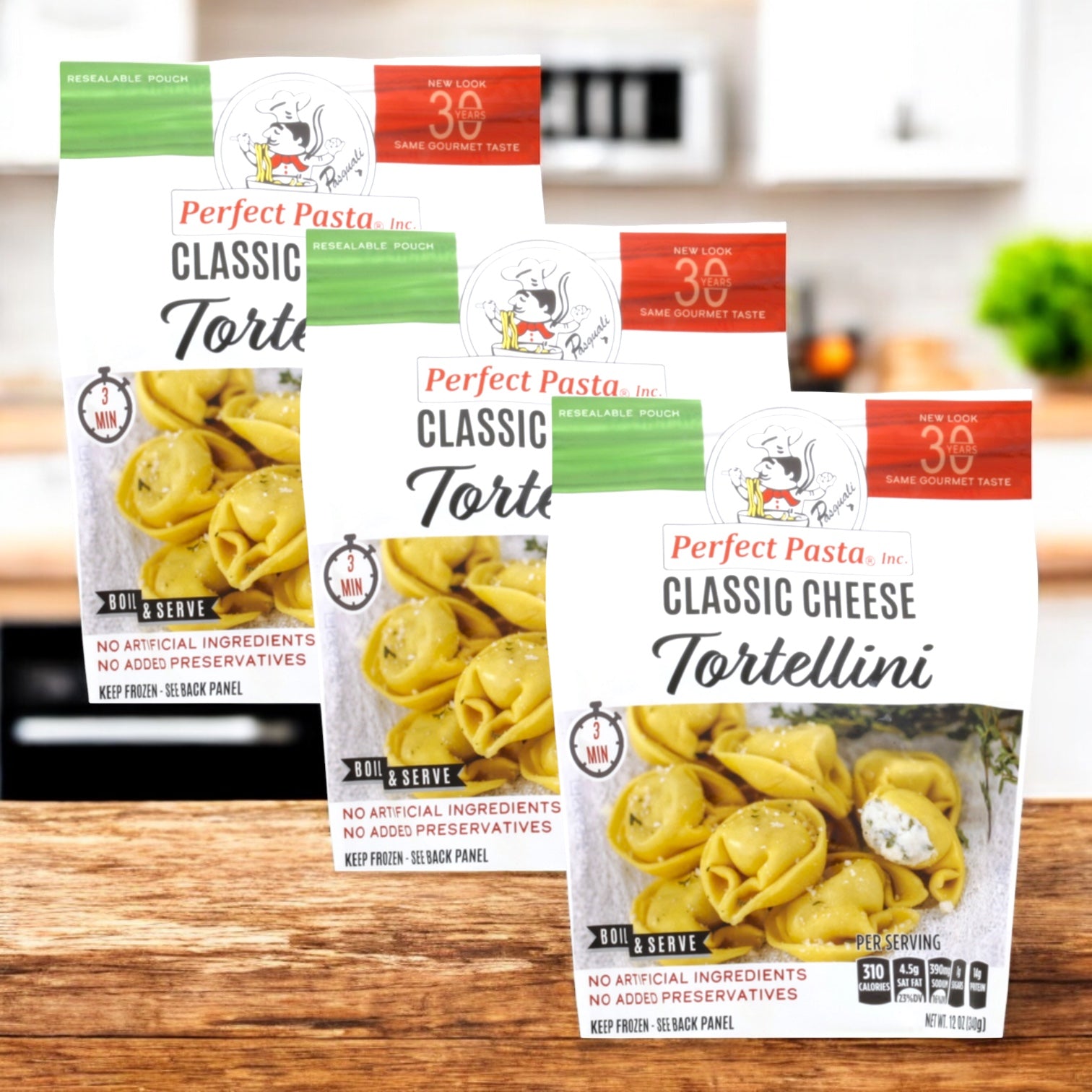 Three packs of Perfect Pasta Classic Cheese Tortellini by Perfect Pasta are shown on a wooden surface with a blurred kitchen background.