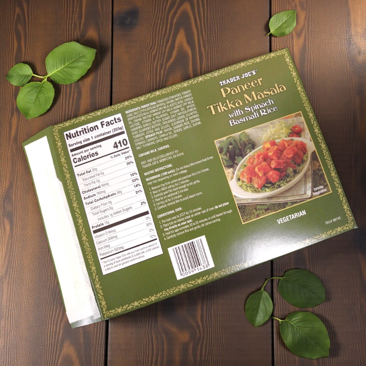 Easy Lunches Trader Joe’s Paneer Tikka Masala with Spinach Basmati Rice, 9 oz. box, featuring nutrition facts, ingredients, and package details, sits on a wooden surface surrounded by green leaves.