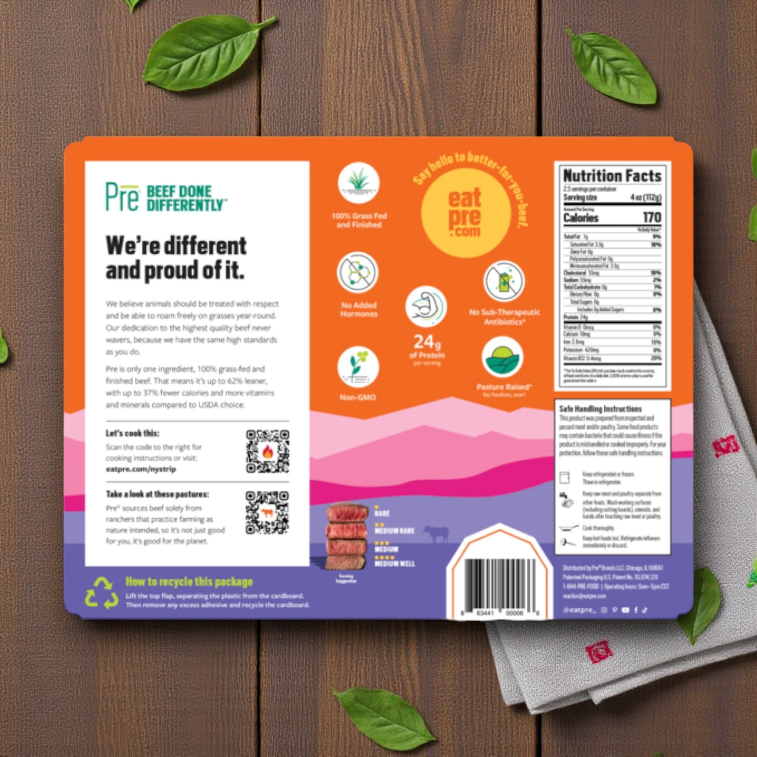 Pre Brands' 100% Grass Fed New York Strip Steak – 10 oz (Fresh Beef) packaging on a wooden surface with green leaves, showing product details, nutrition info, recycling instructions, and QR codes.