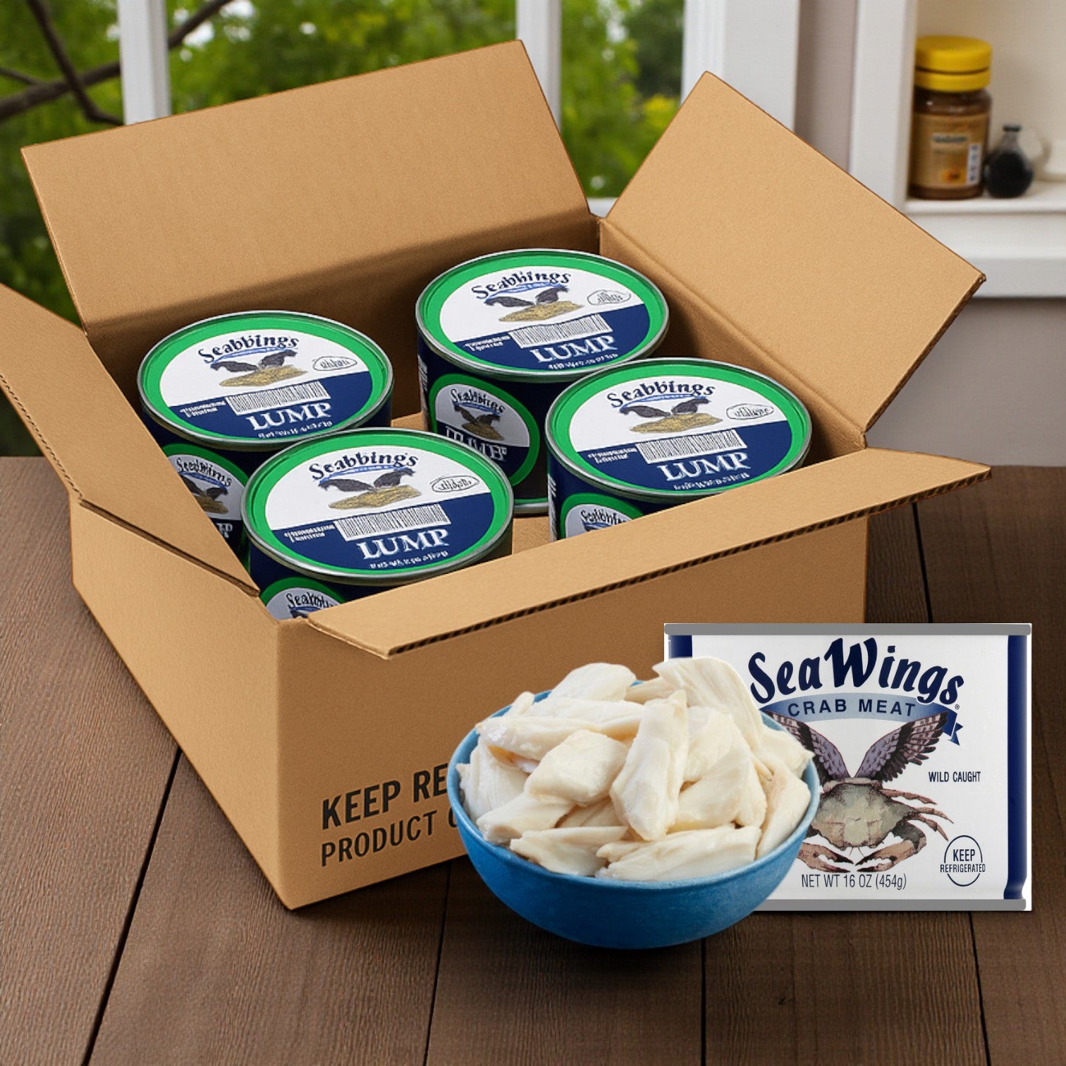 An open box of Sea Wings Pasteurized Lump Crab Meat, 1 lb cans (6 count case), sits on a table beside a bowl of crab meat and a sealed Sea Wings package.