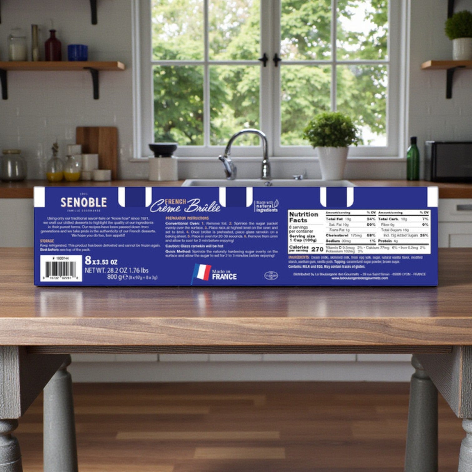 A box of Senoble French Crème Brûlée, 3.75 oz, 8-Count sits on a wooden kitchen island in a bright kitchen, with nutrition facts and labeling clearly visible.